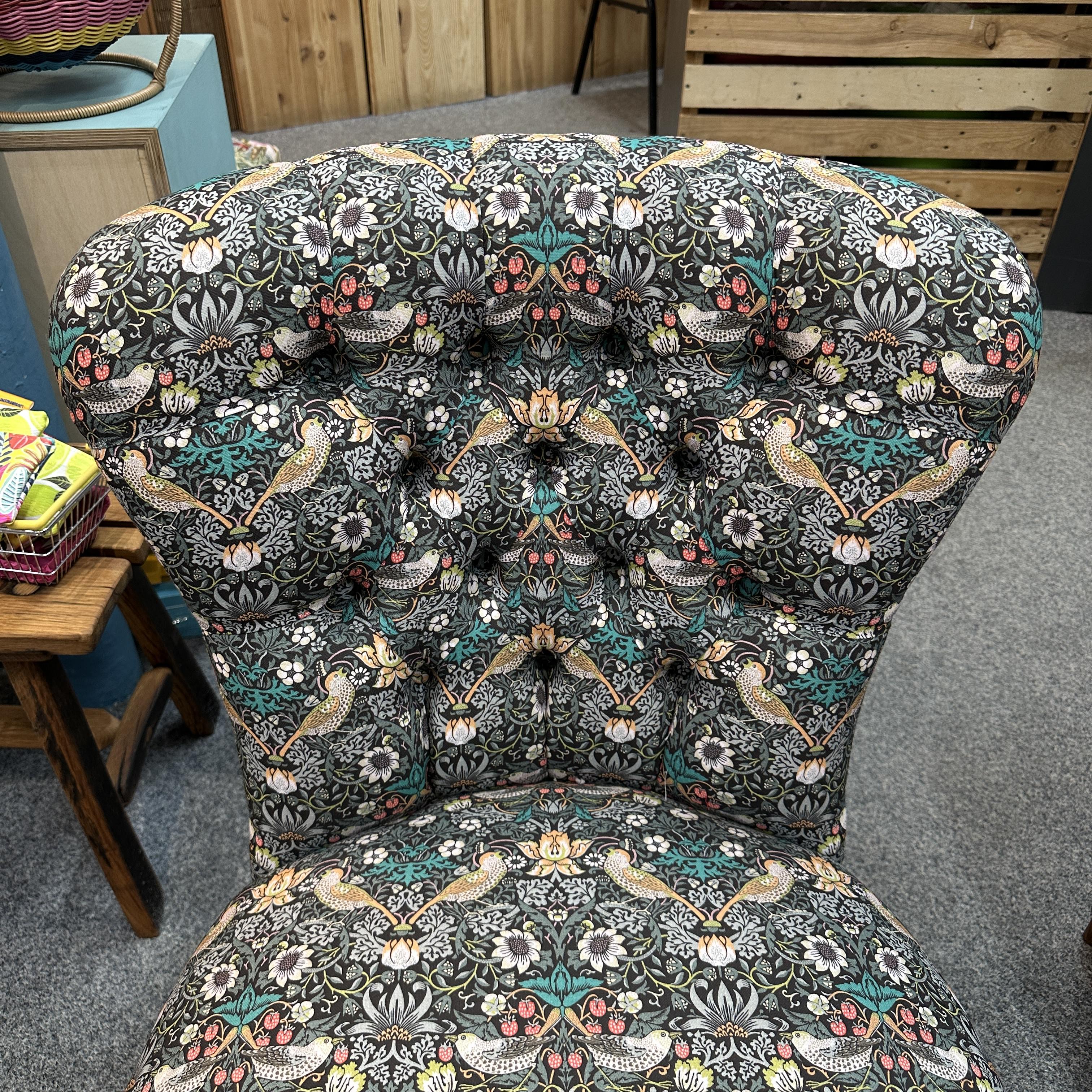 Decorative armchair with intricate floral and bird pattern in a room setting.