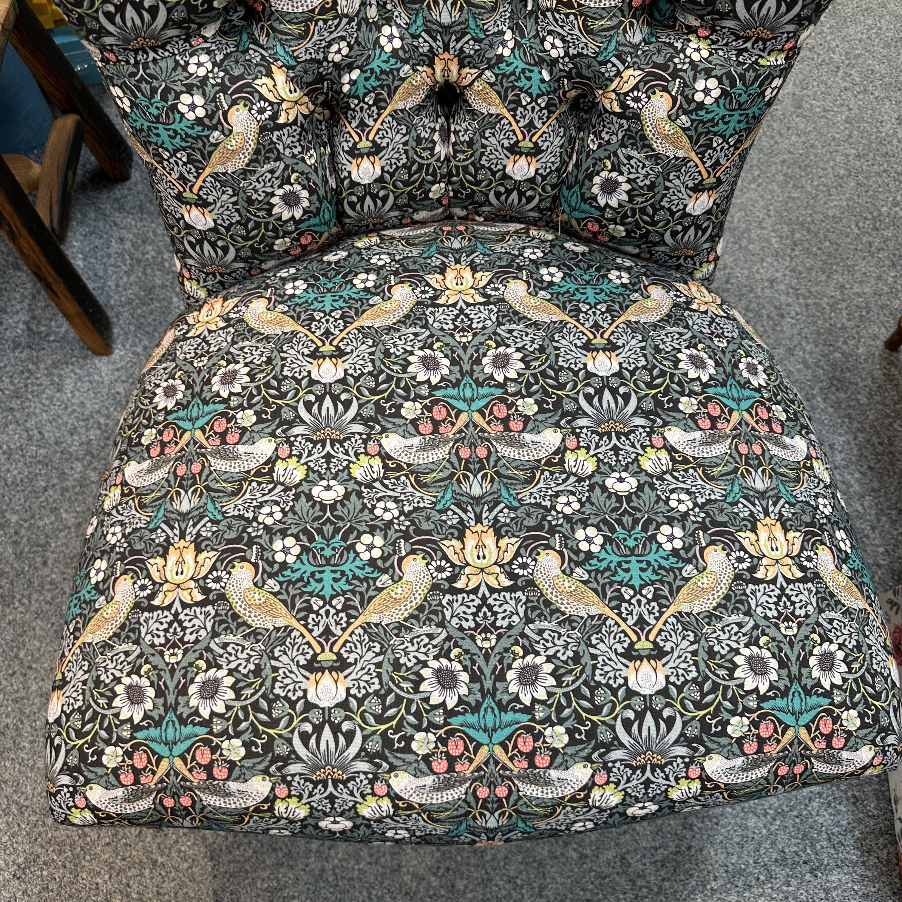Chair with decorative floral and bird pattern on a gray floor.
