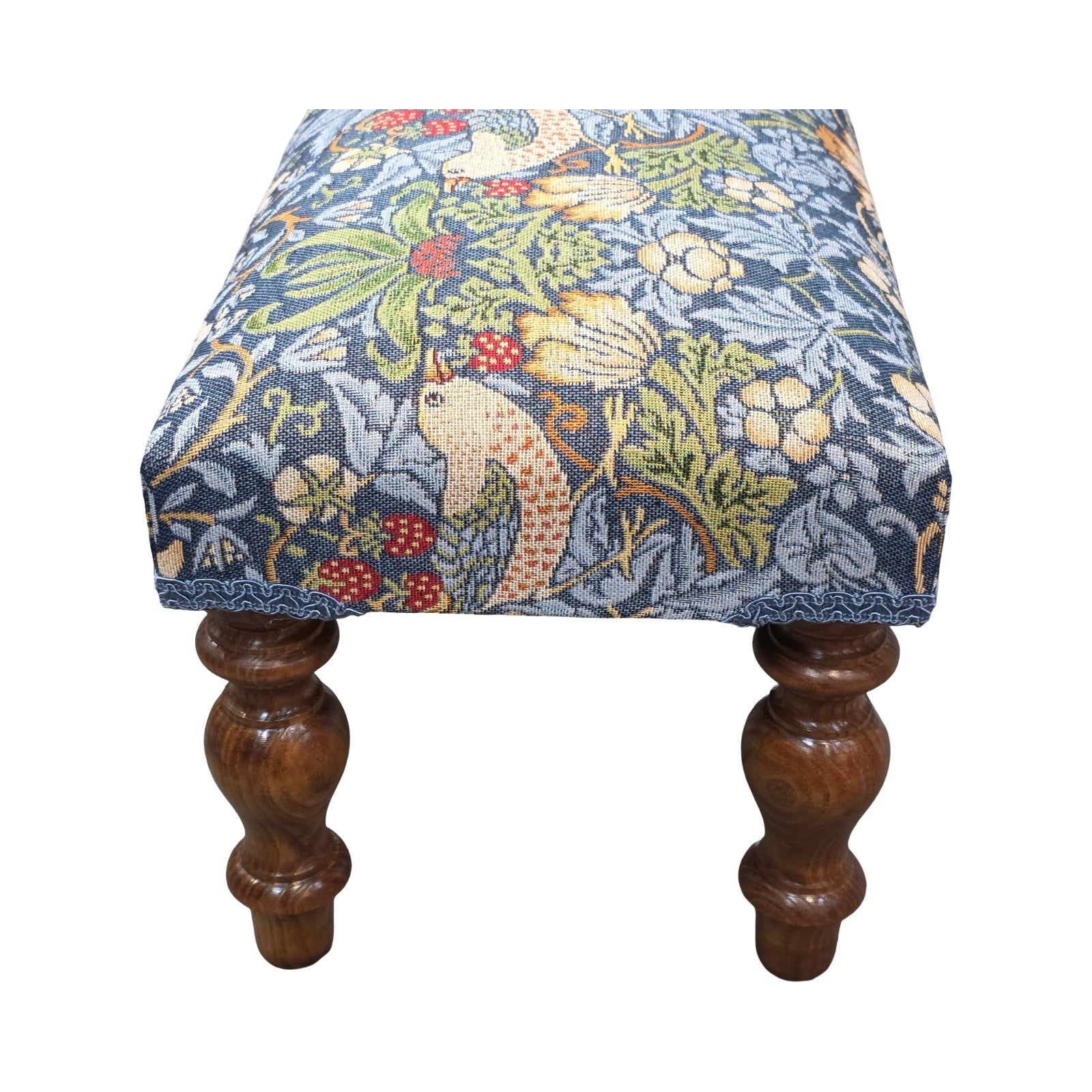 Small stool with floral patterned cushion and wooden legs on a white background.