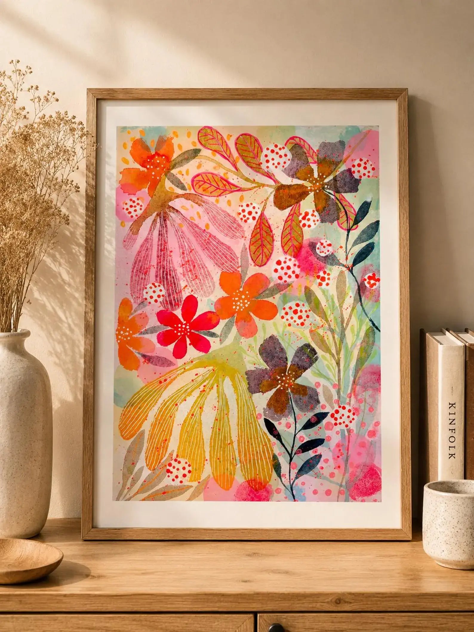 Framed colourful floral artwork on a wooden shelf with decorative items.