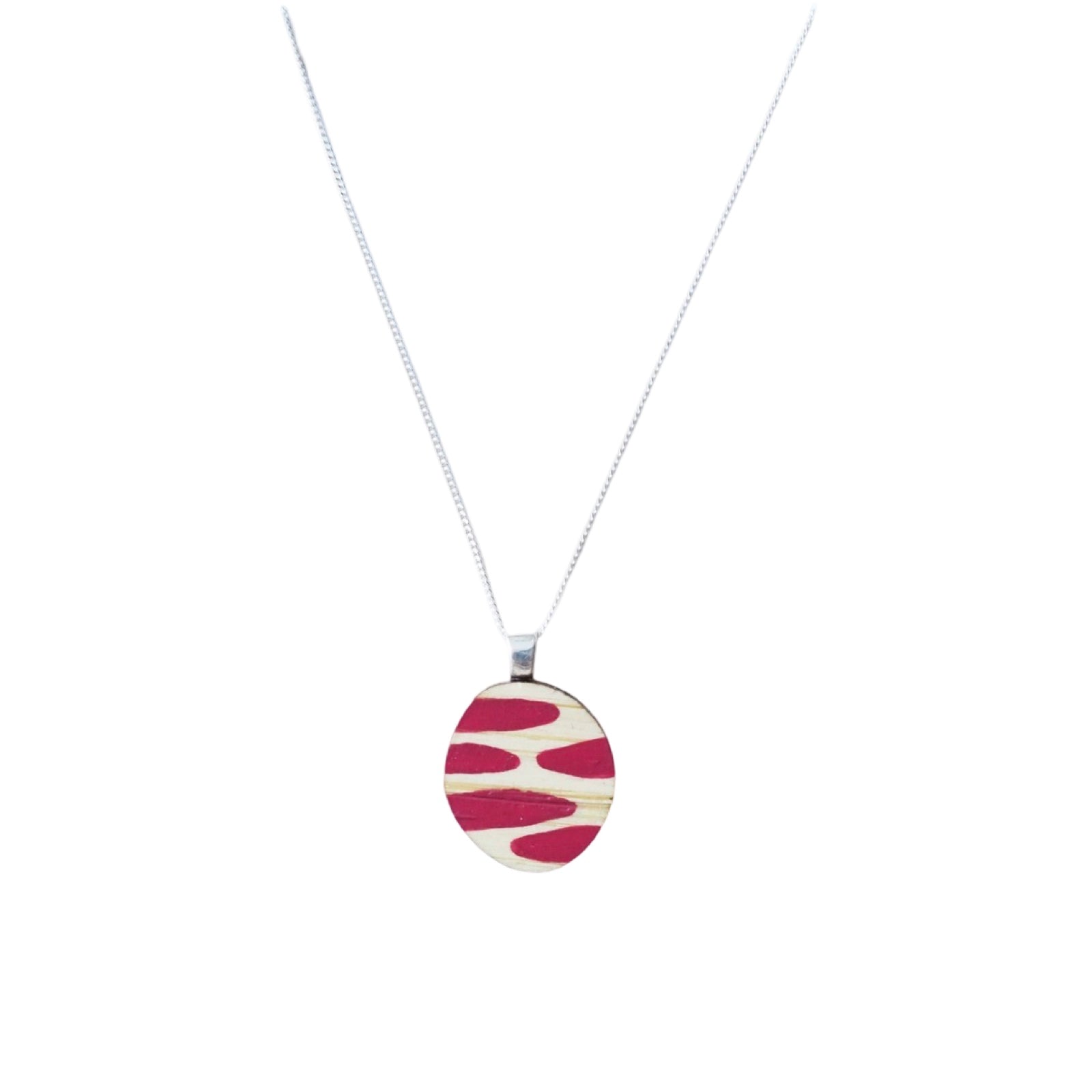 A small wooden necklace with a pink dashed painted pendant and a sterling silver chain.