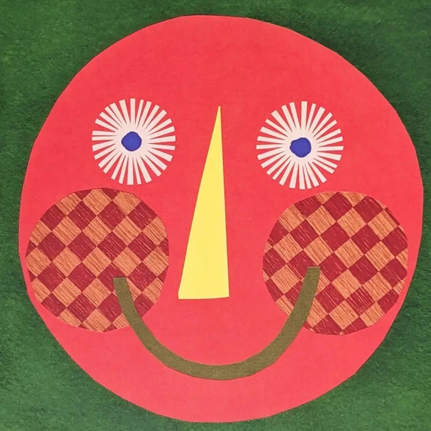 Artwork with a red face design on a green background.