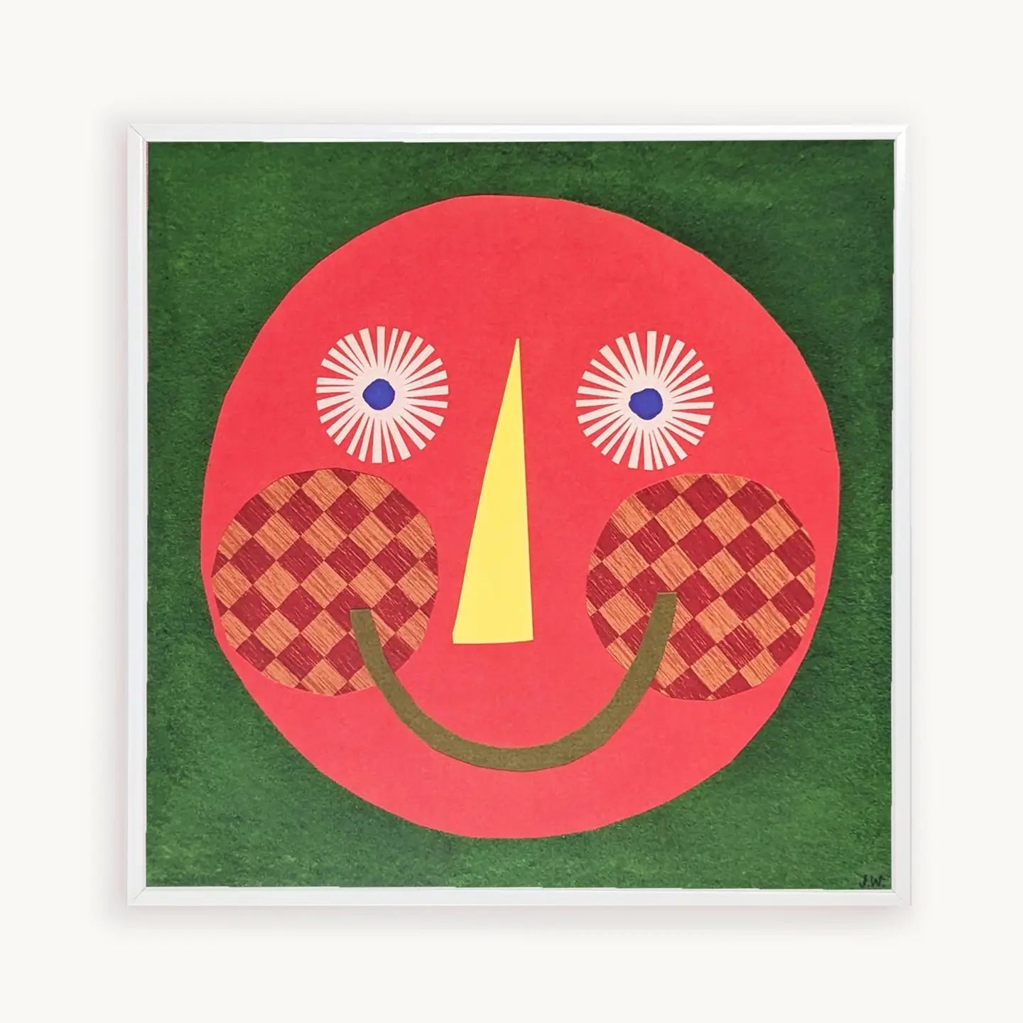 Framed artwork with a red face design on a green background.