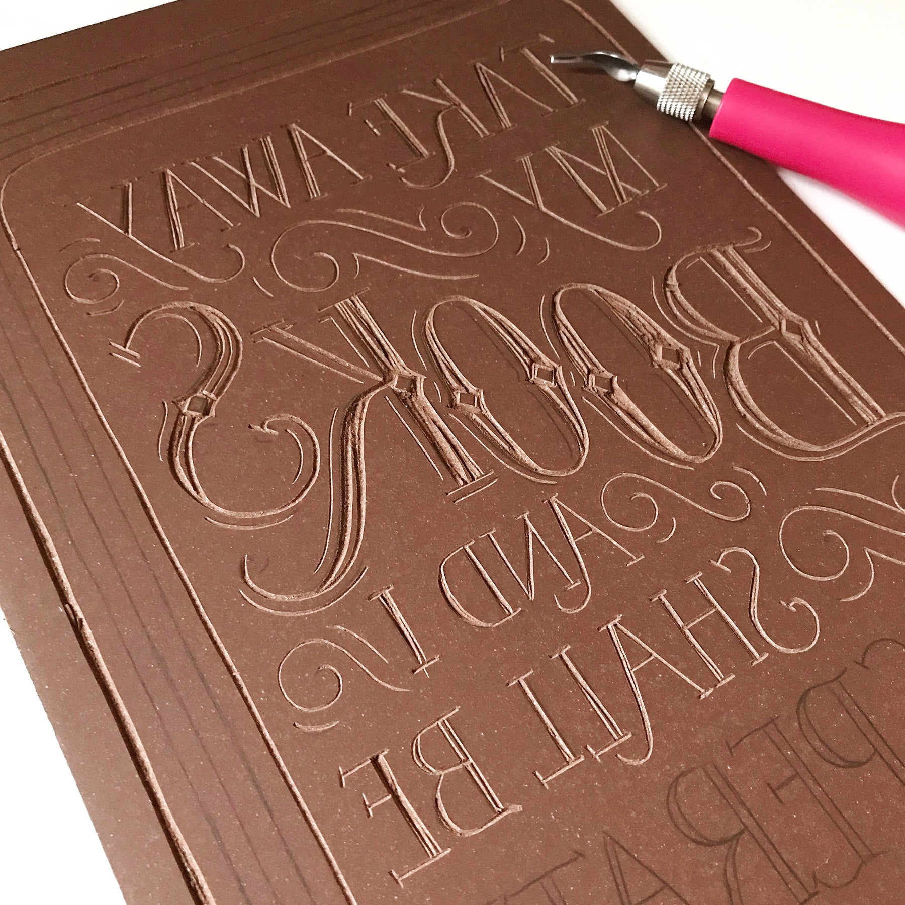 Brown embossed book with a tool on a white background.