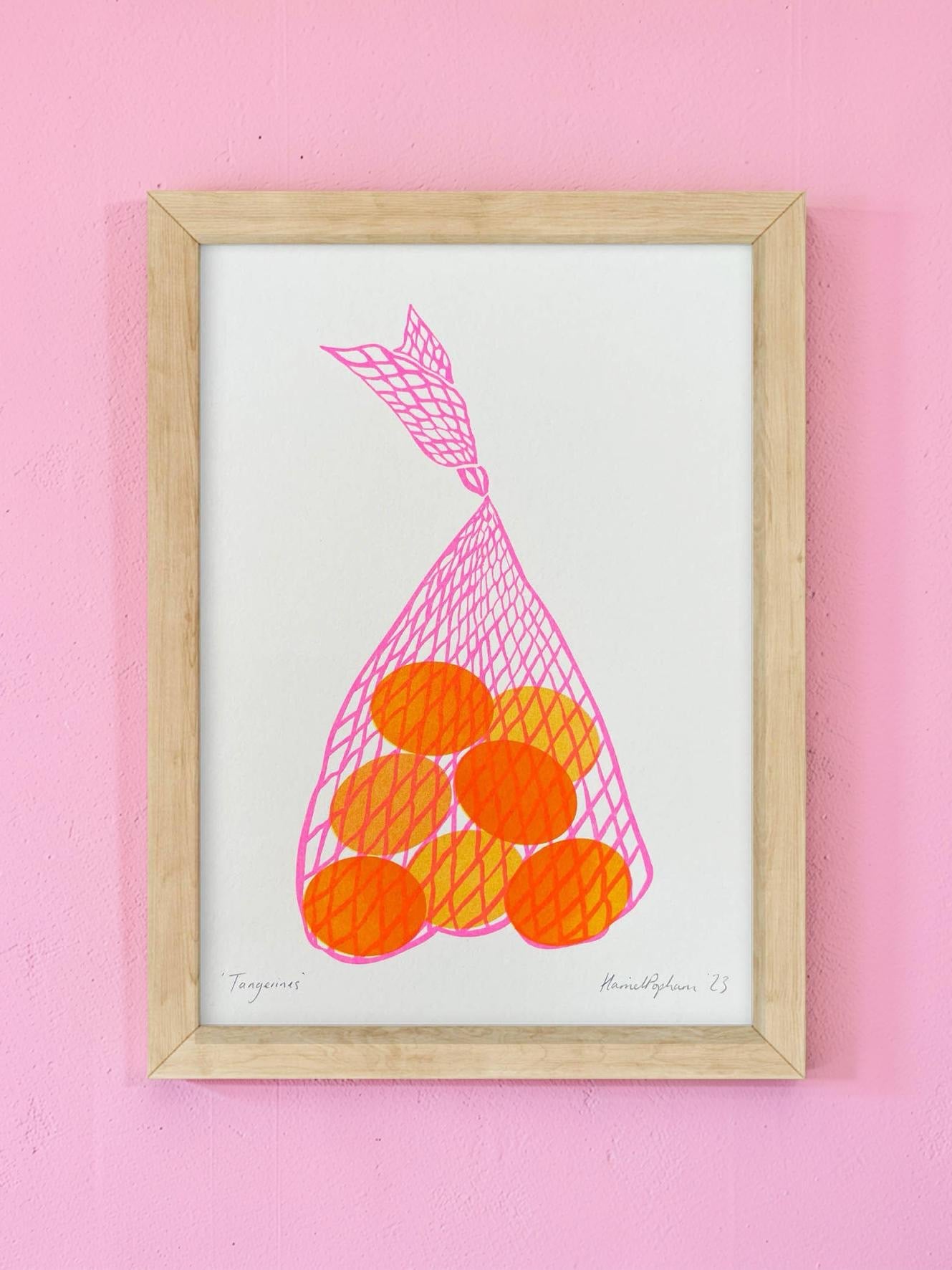 Framed artwork of a pink bag of oranges on a pink background.