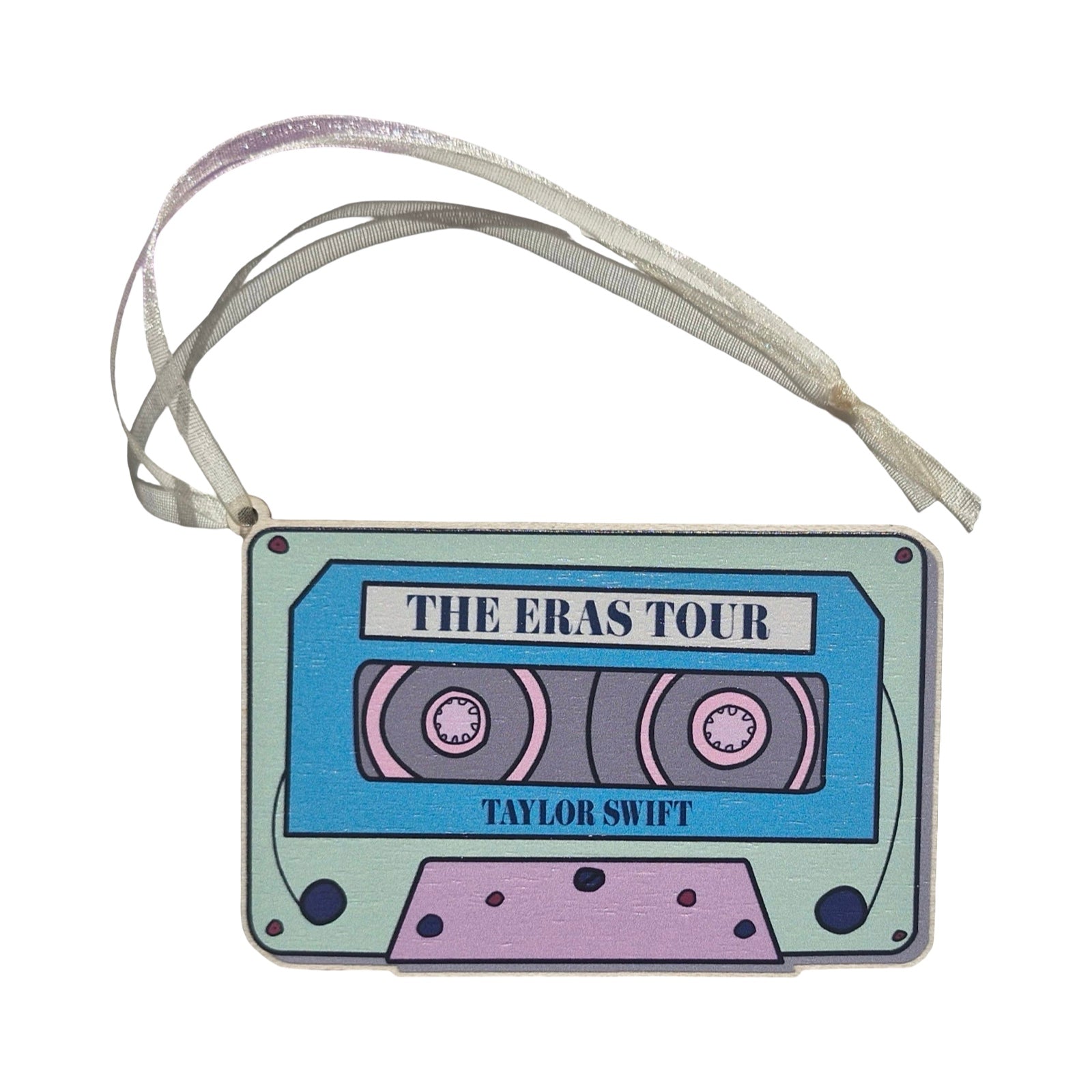A rectangular-shaped wooden decoration featuring an illustration of a retro cassette tape in blue, pink and aqua with the title 'The Eras Tour, Taylor Swift'. 