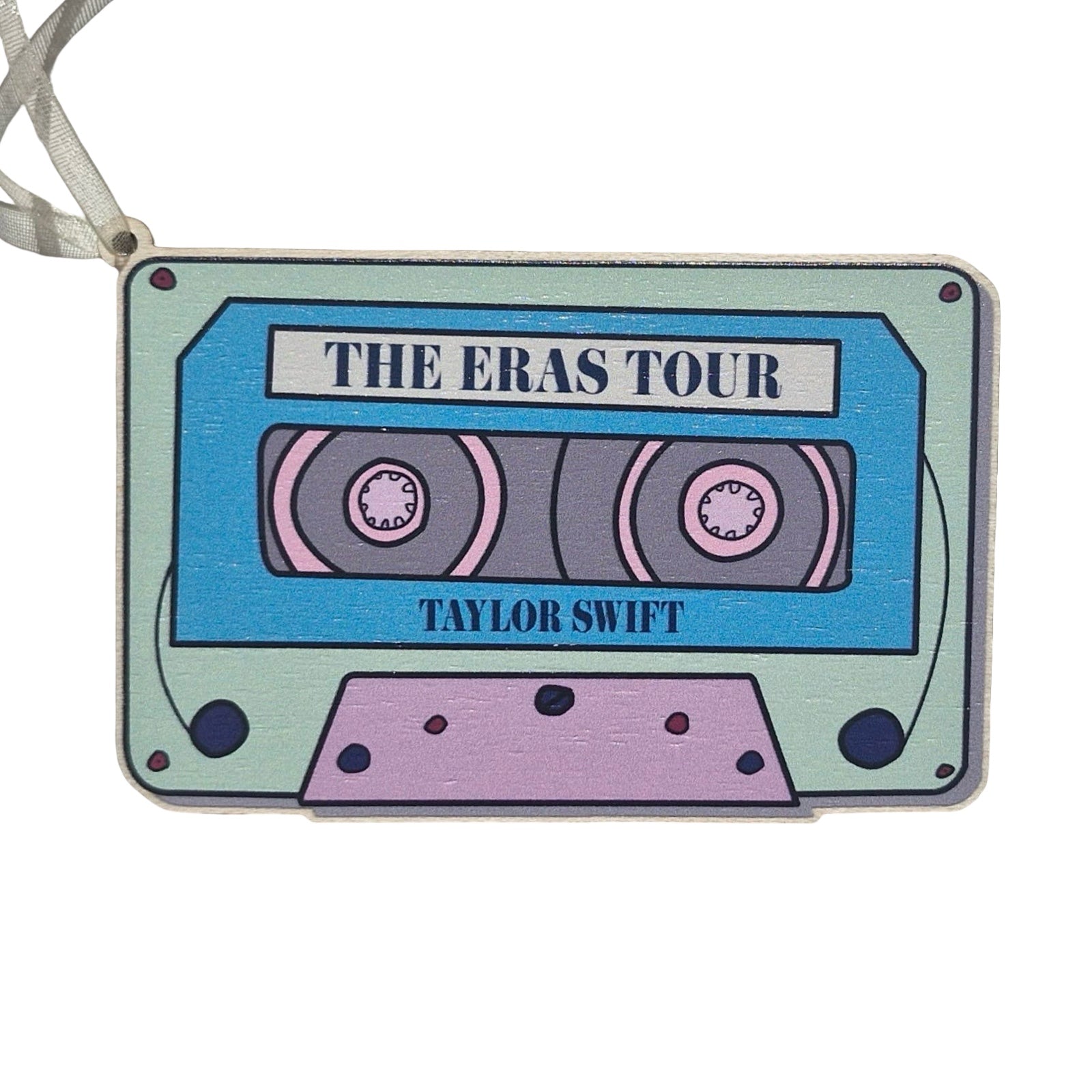 A rectangular-shaped wooden decoration featuring an illustration of a retro cassette tape in blue, pink and aqua with the title 'The Eras Tour, Taylor Swift'. 