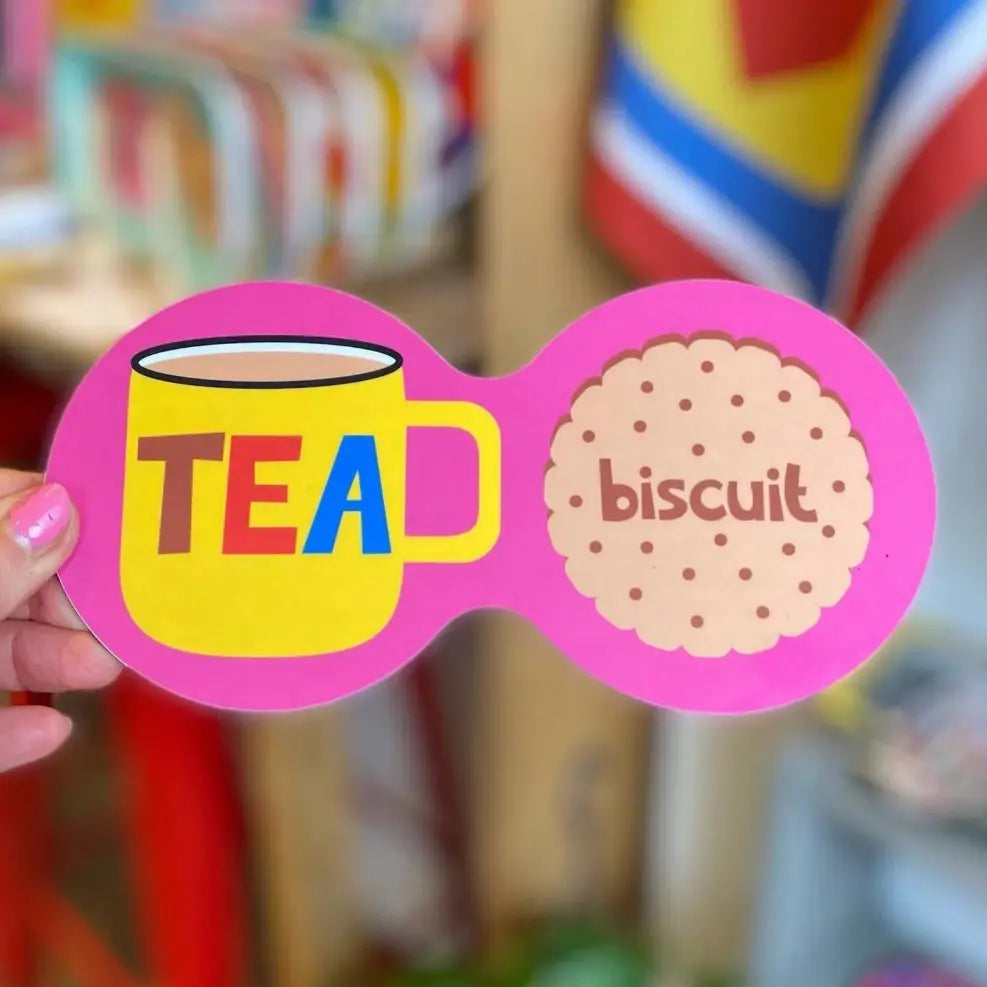 Coaster with a tea cup and biscuit design held by a hand.