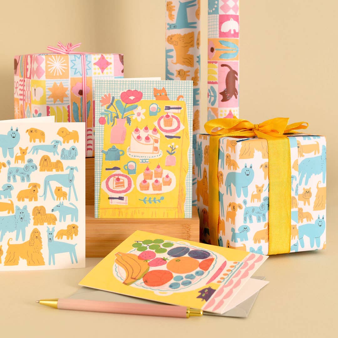 Colourful stationery items including notebooks, cards, and a pen on a beige background.