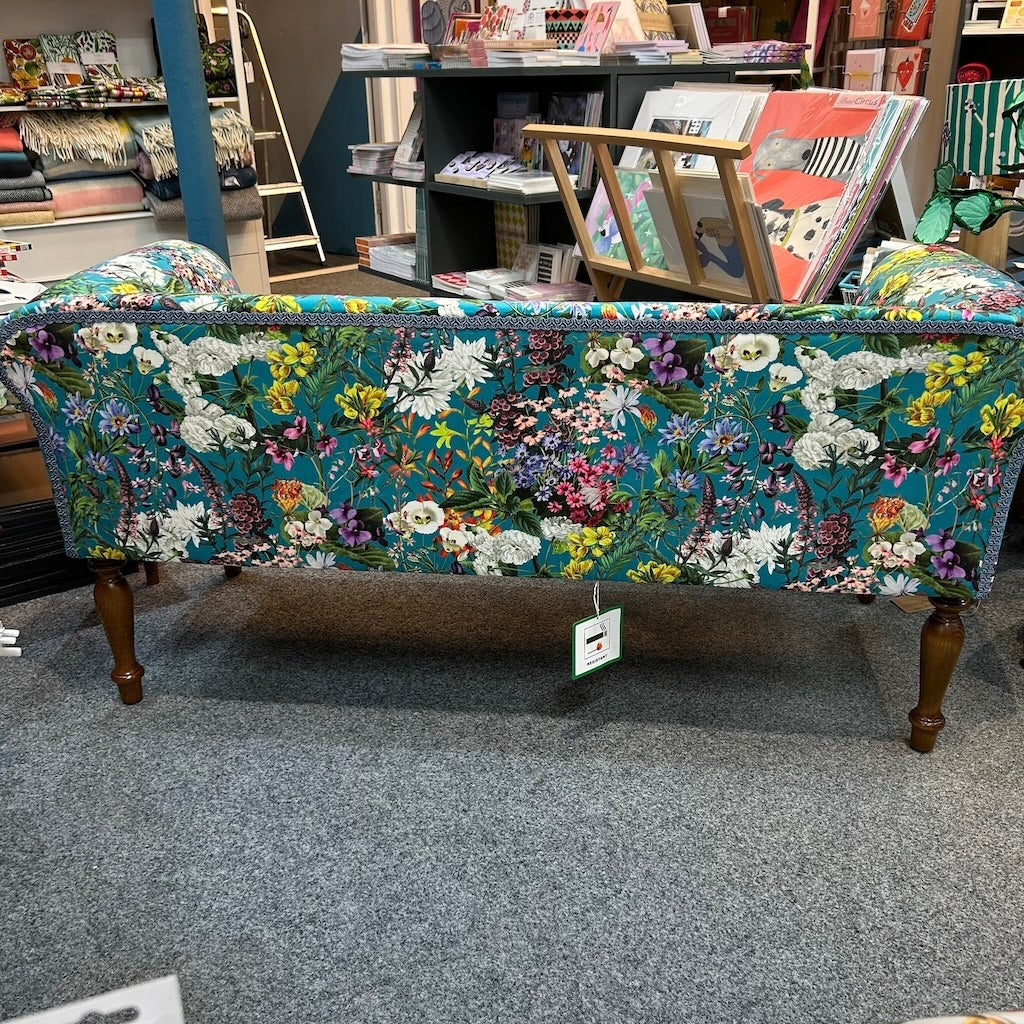 A beautiful hand crafted occasional low backed sofa covered in gorgeous teal floral velvet with mahogany stained legs.
