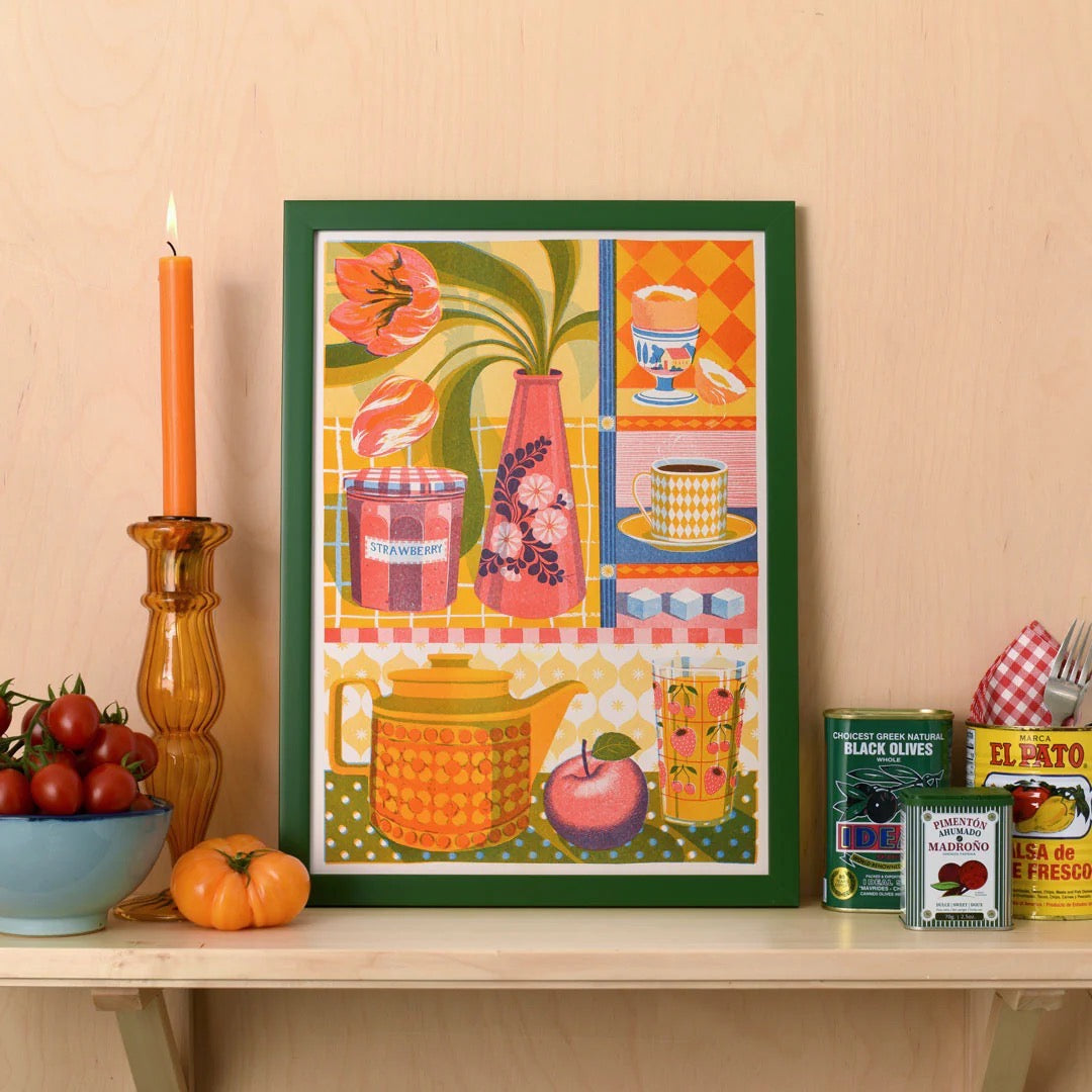 Framed colorful artwork on a shelf with decorative items.