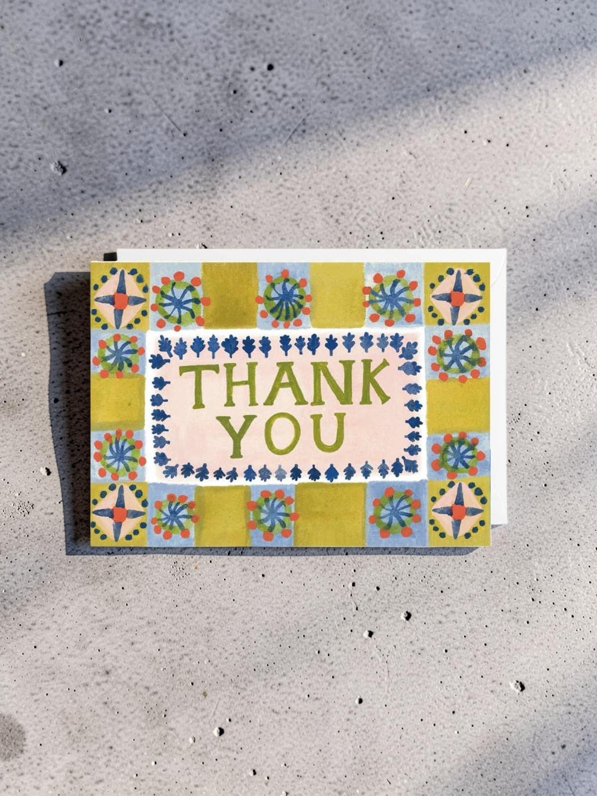 Colorful card with 'Thank You' text on a textured surface.