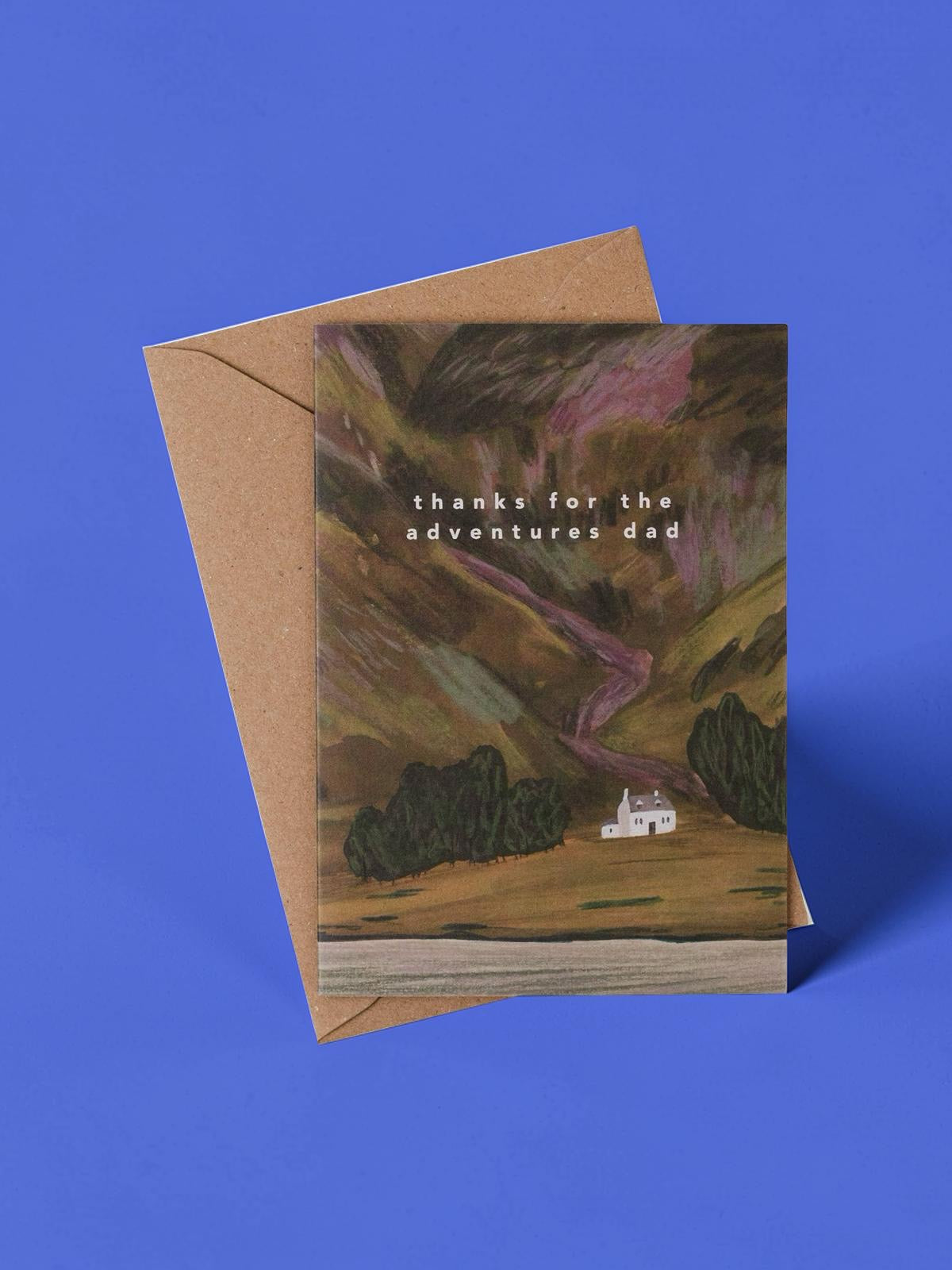 Father's Day card featuring an illustration of a mountain with a bothy below and the text 'thanks for the adventures dad' on a blue background.