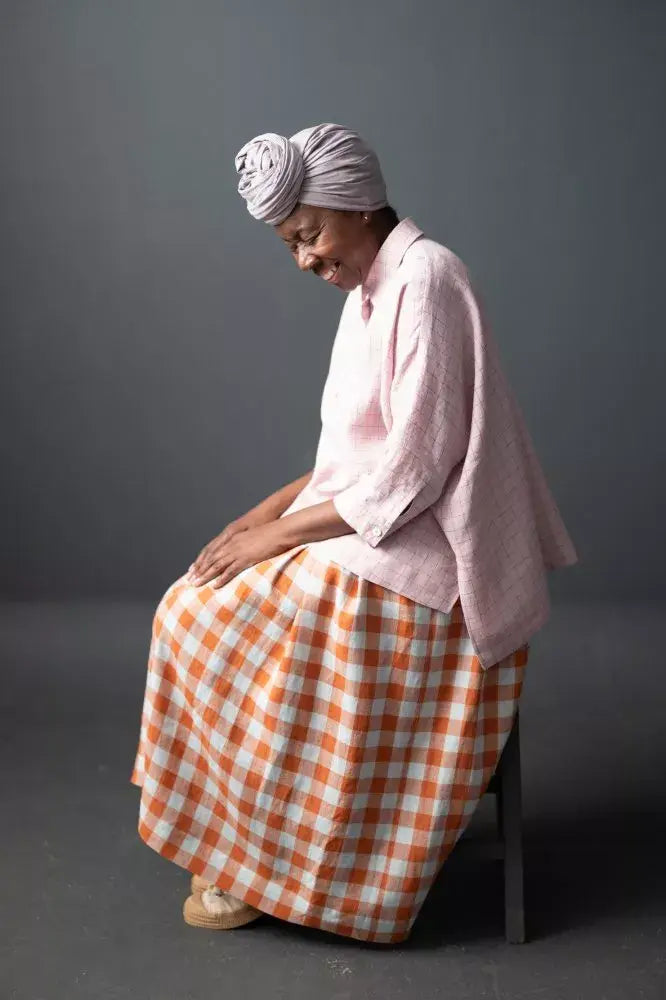 Sewing pattern for an A-line skirt with slanted pockets, side button fastenings and pleats for fullness.