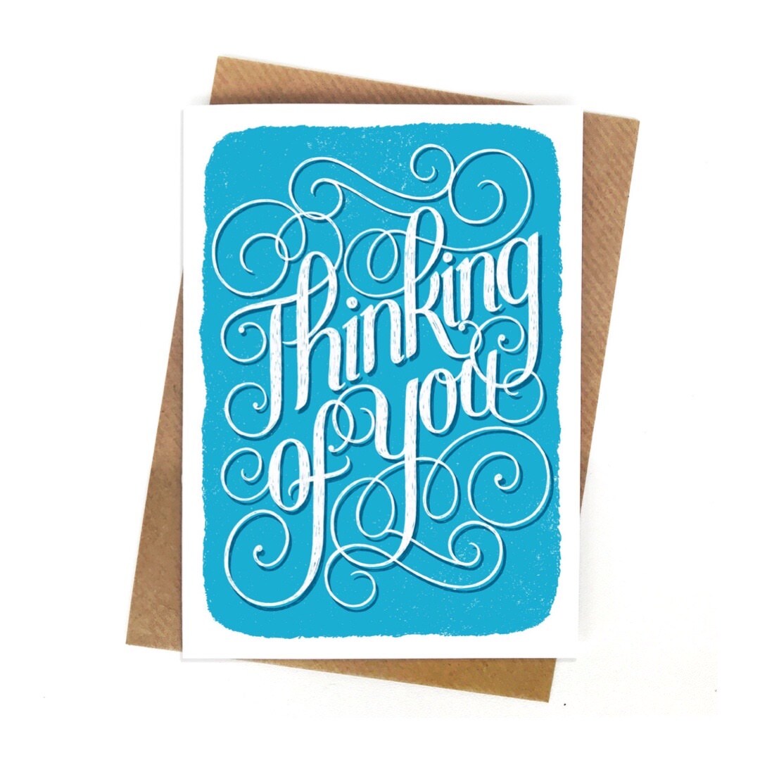 A sympathy card with the text 'thinking of you 'in white lettering on a pale blue background