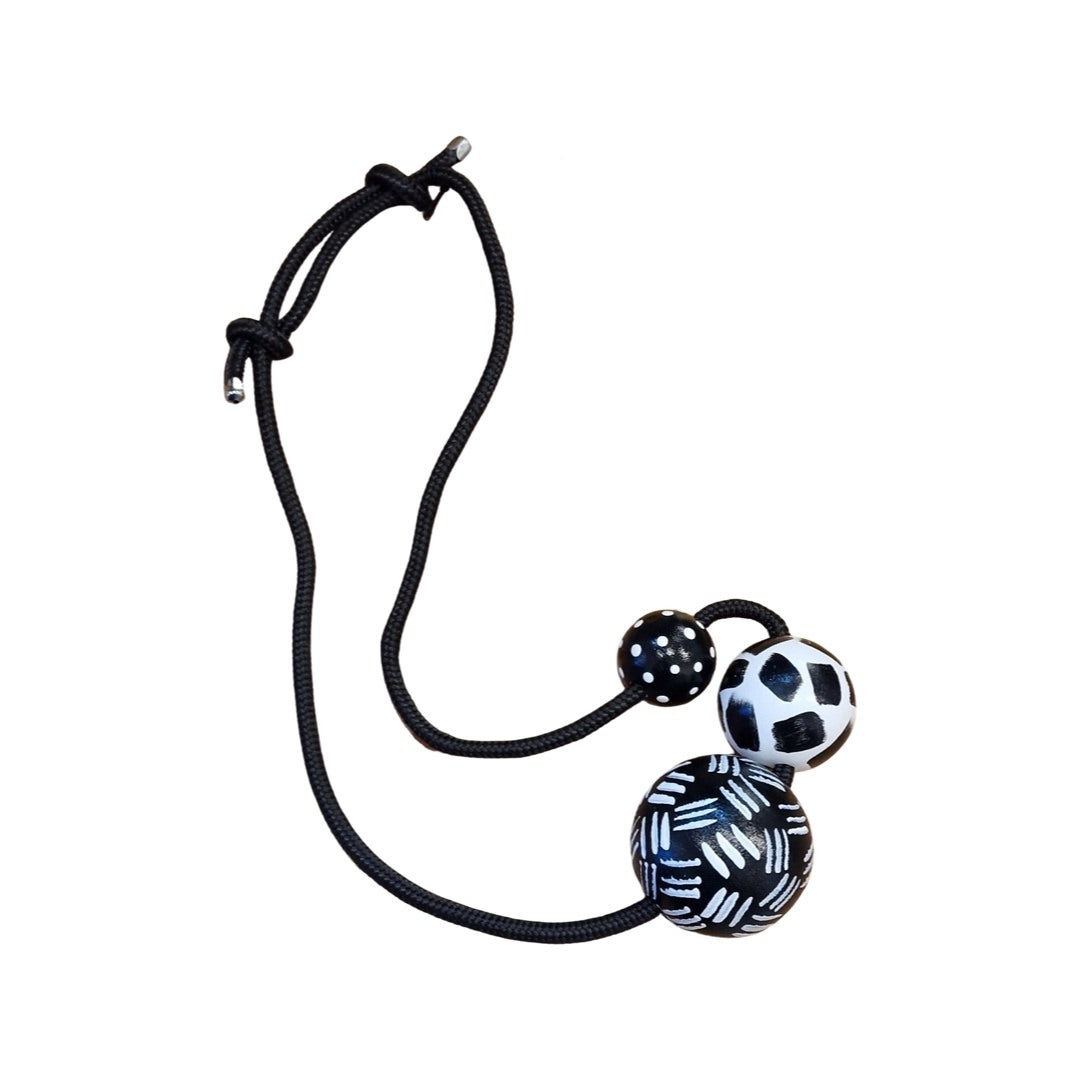 A black and white chunky necklace with three beads featuring dashes, strokes, and polka dot patterns, strung on black braided soutache rope, with an adjustable length.