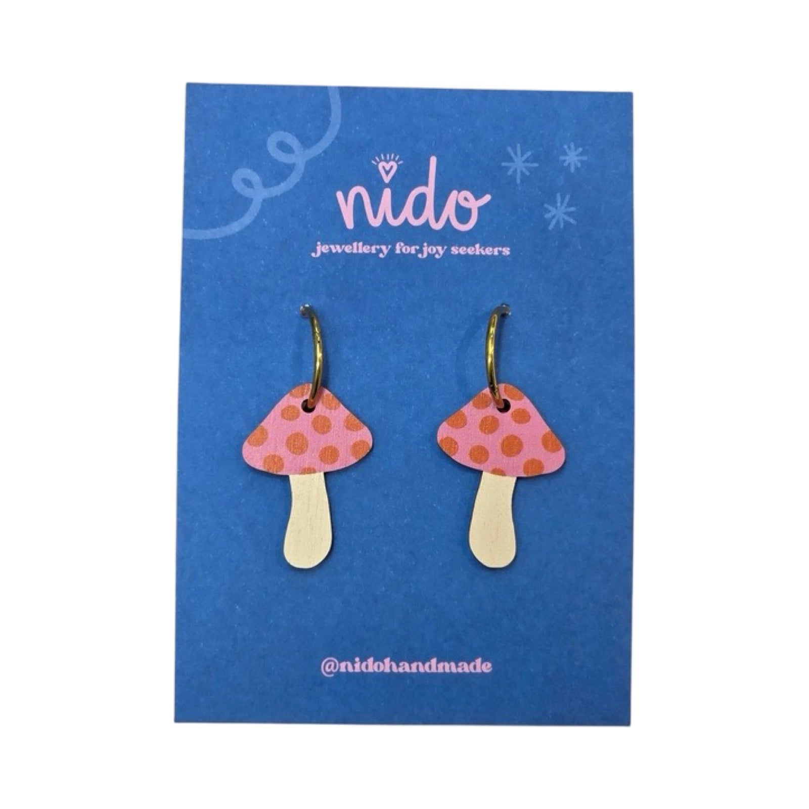 Toadstool shaped drop earrings in pink with red polka dot tops and gold plated stainless steel hoops, presented on a branded blue backing card.