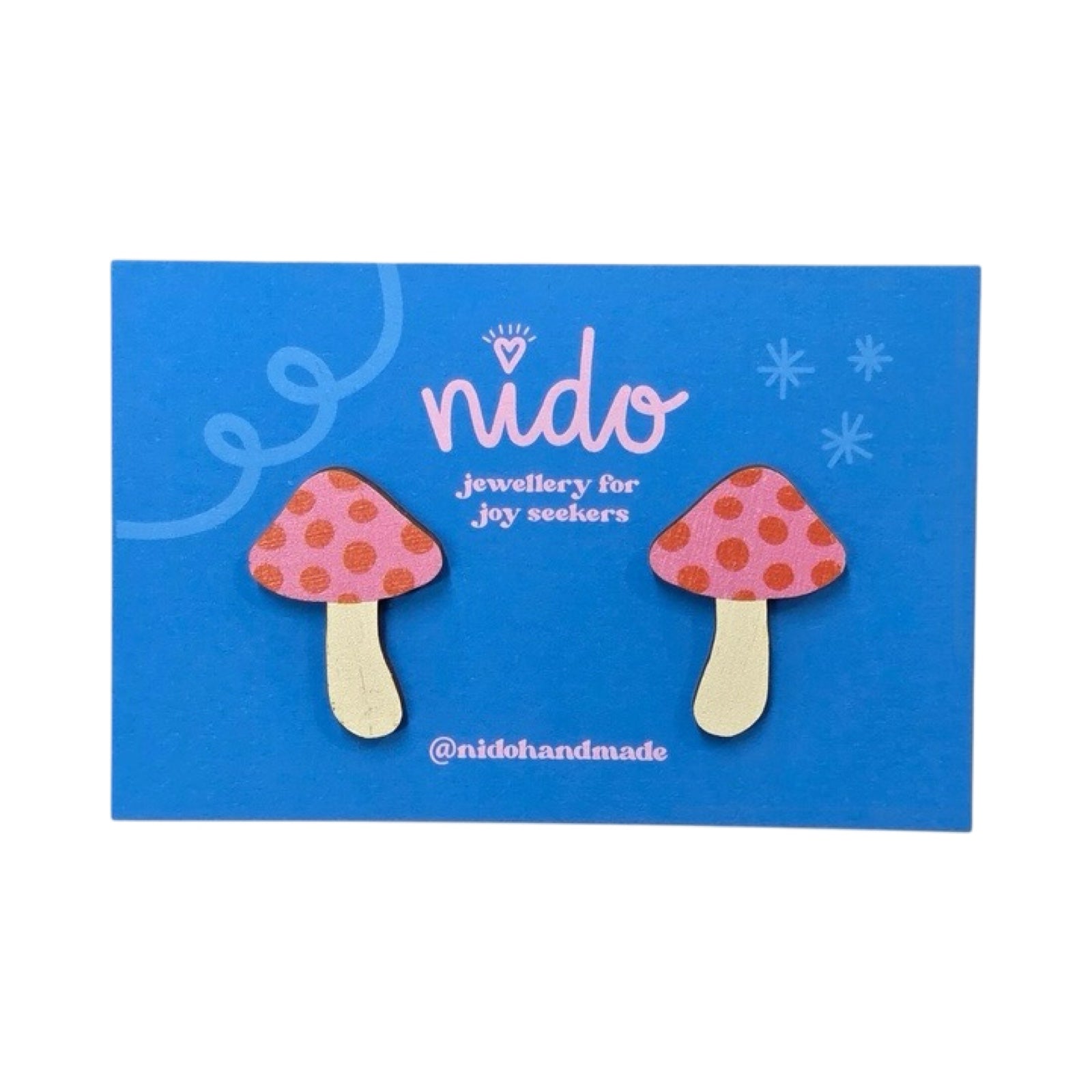 Toadstool stud earrings with pink and red spotty tops on a blue backing card.