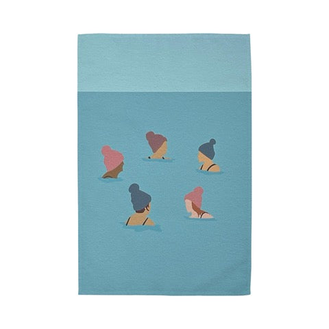 Tea towel featuring a group of wild swimmers in their woolly pom-pom hats up to their shoulders in the sea.
