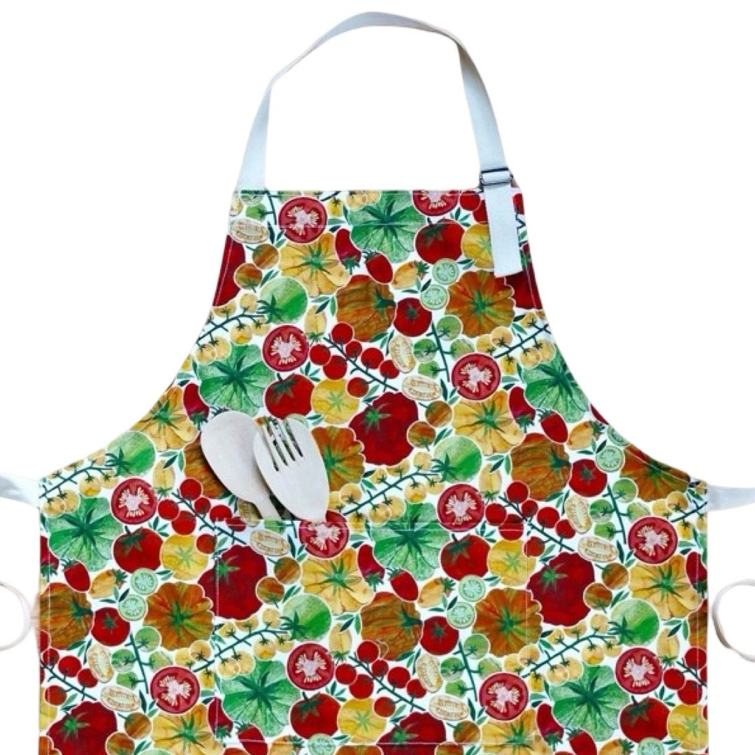 Apron featuring red, orange and yellow tomatoes with green foliage on a white background.