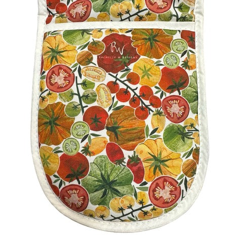 Oven gloves featuring red, orange and yellow tomatoes with green foliage on a white background.