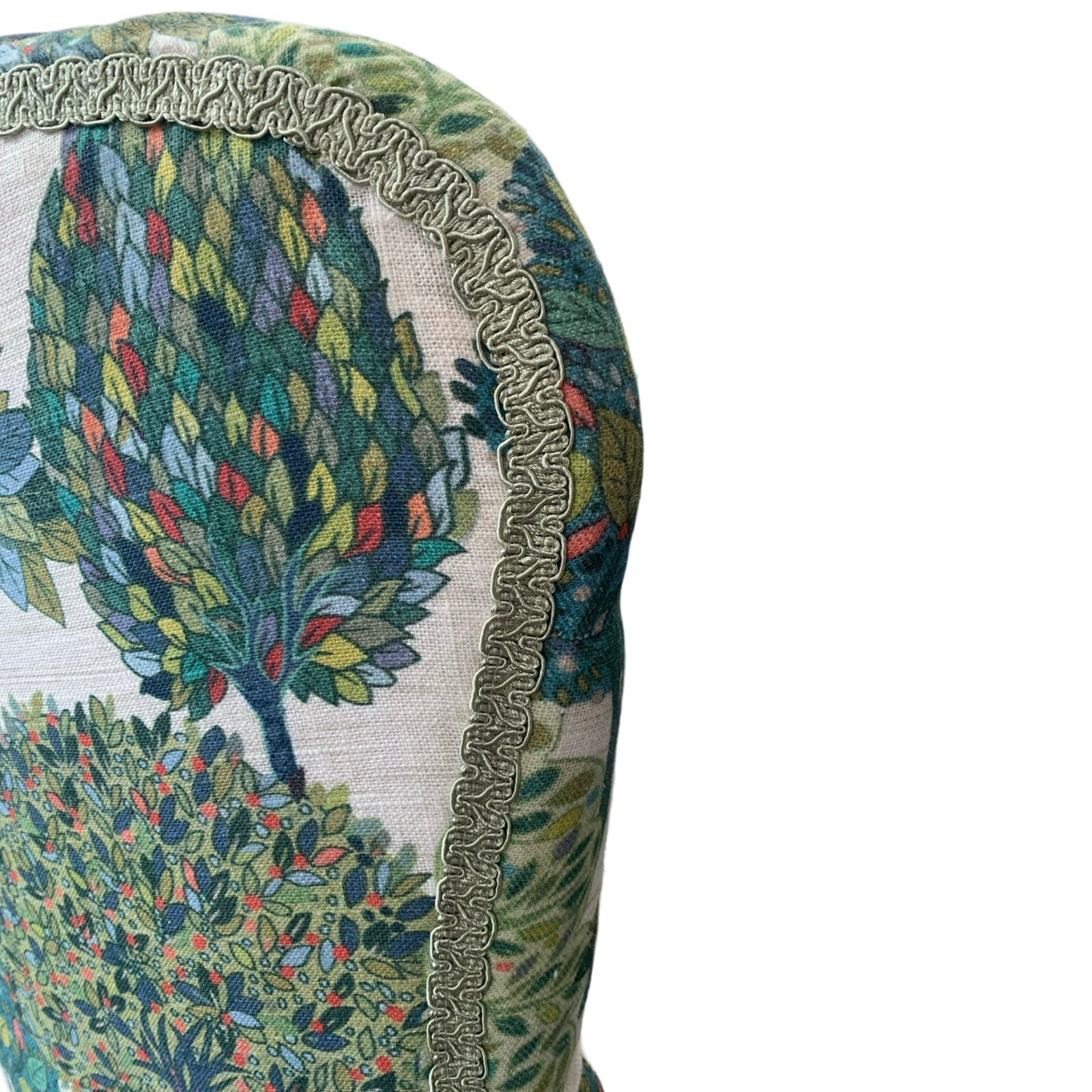 A cream linen armchair with a blue and green tree pattern, featuring a button-back design, mahogany legs, and gold castors.