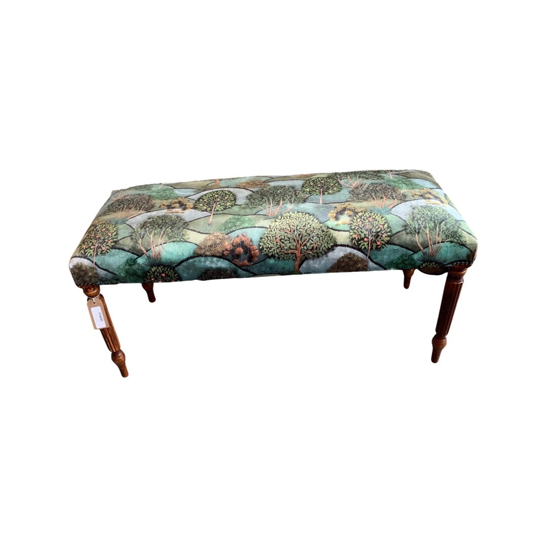 A hand-crafted rectangular bench covered in multicolored velvet fabric with a tree pattern, featuring metal studs and wooden legs.
