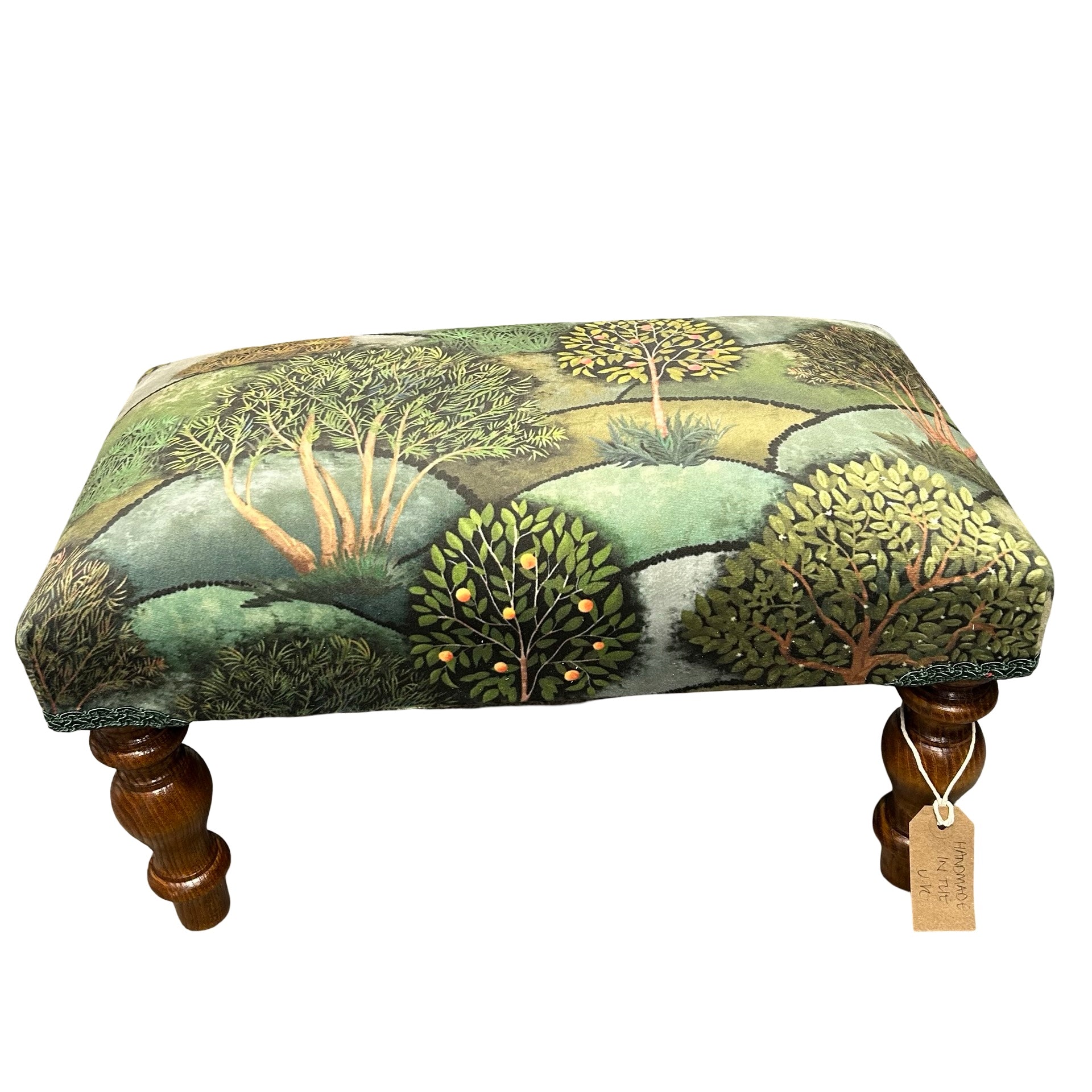 Footstool with nature-themed fabric and wooden legs on a white background.