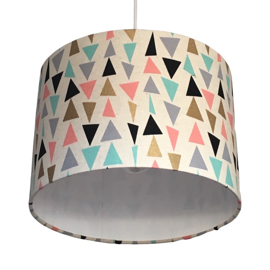 Close up of a cream drum lampshade with mint, pink, black, grey and gold triangles