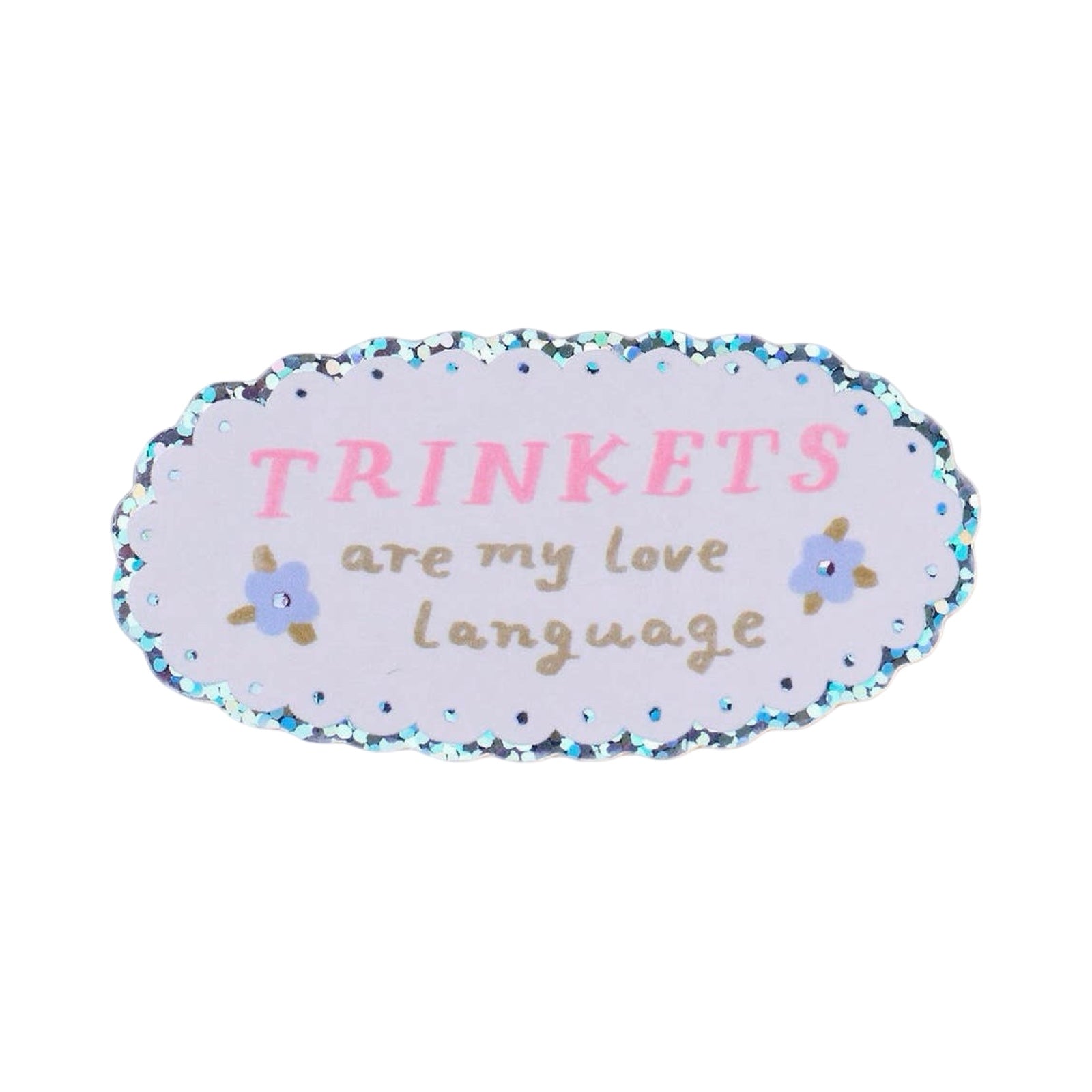 An oval-shaped sticker with a glittery blue scalloped border, featuring the text 'TRINKETS are my love language' in pink and brown lettering, accented with small blue flowers, on a white background.