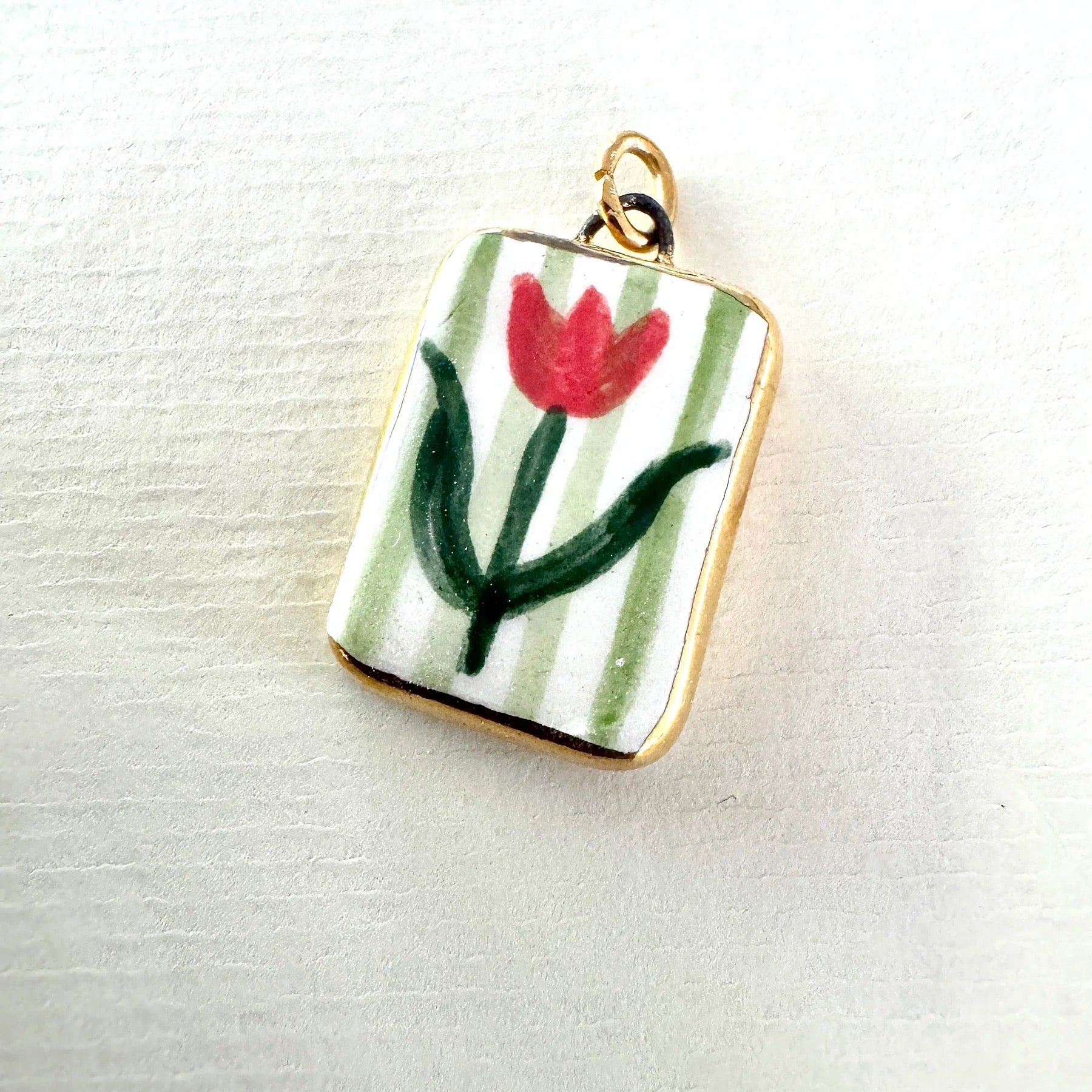 Pendant with a red flower design on a striped background.