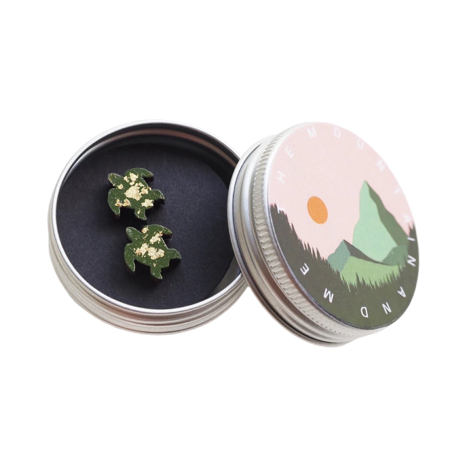 A pair of green turtle-shaped stud earrings in a small round metal tin.