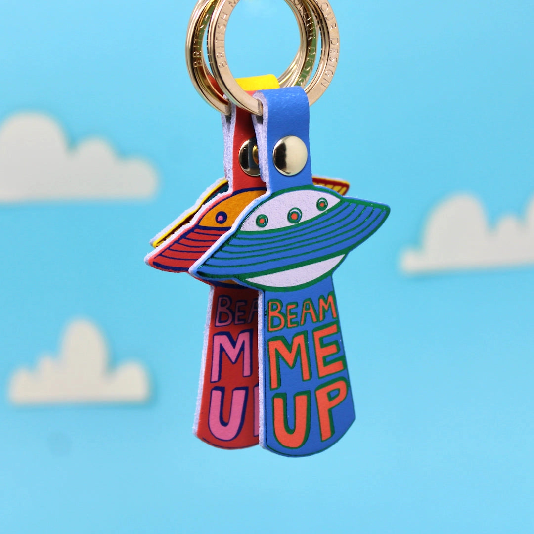 Colourful UFO key rings with 'Beam Me Up' text on a blue background.