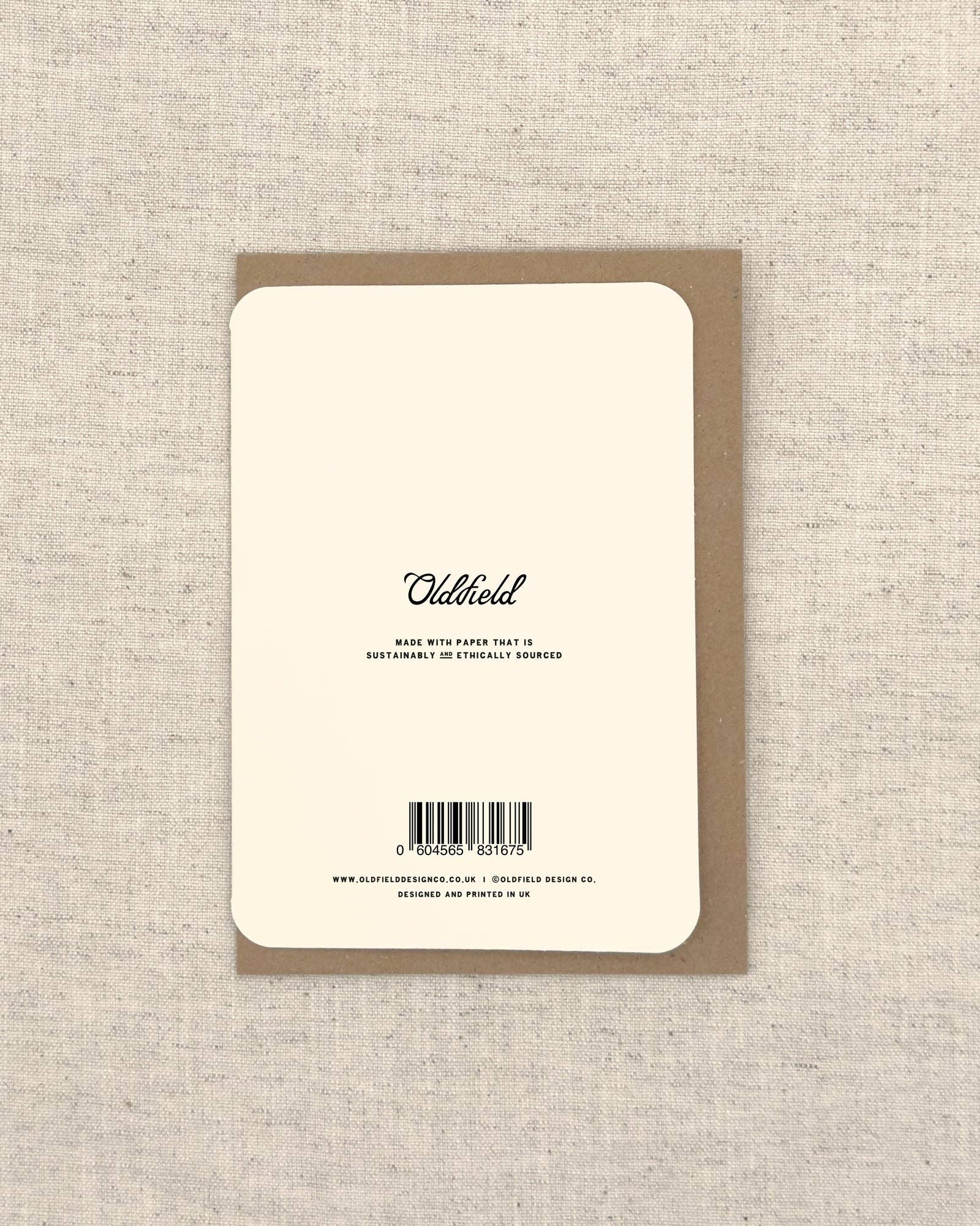 Back of a greeting card with 'Oldfield' branding and sustainability information on a textured beige background.