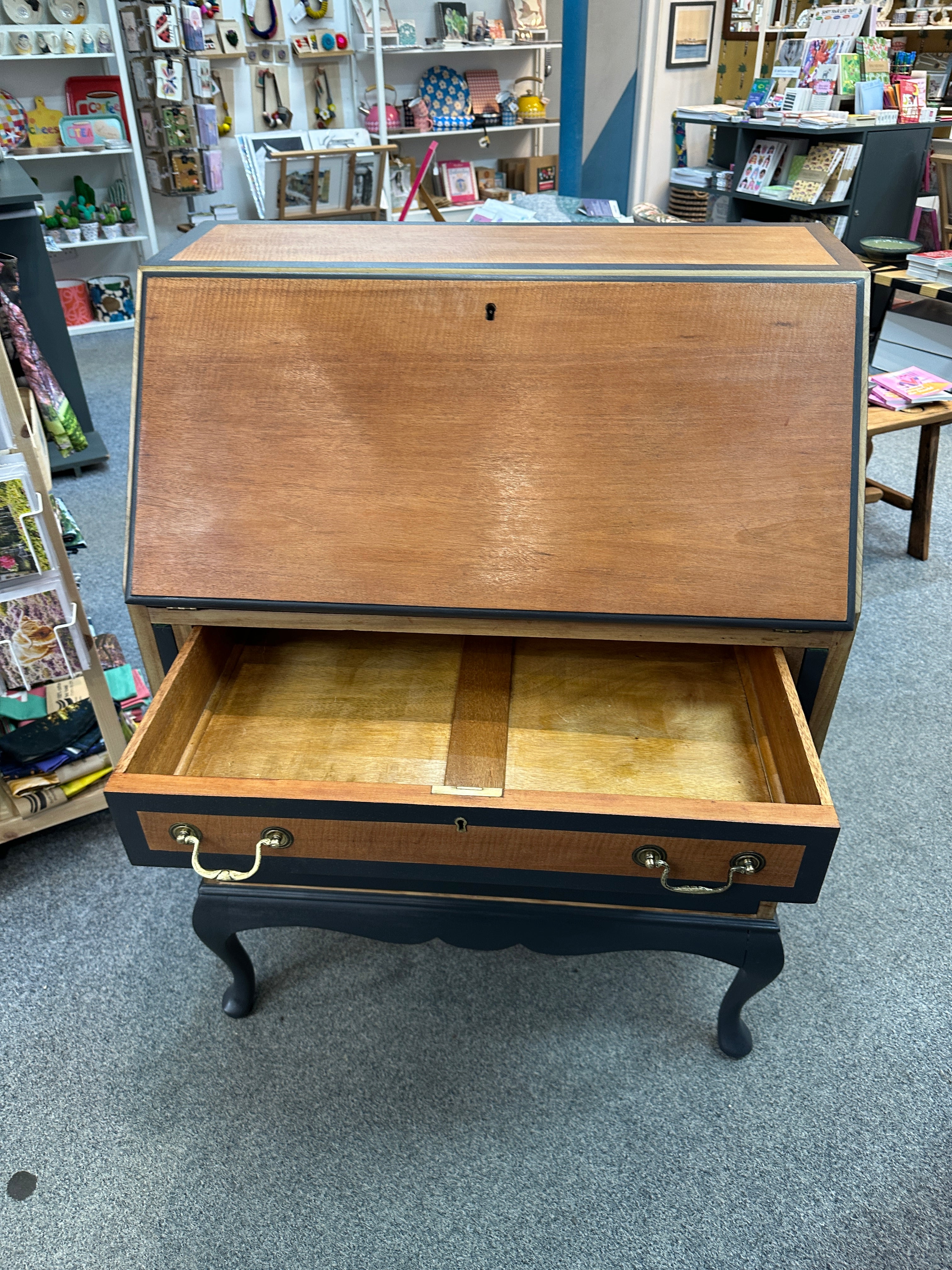 Wooden desk with open drawer in a store setting.