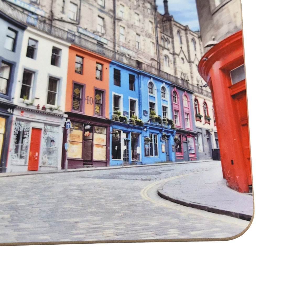 Colorful buildings on a street corner with a red building on a coaster.
