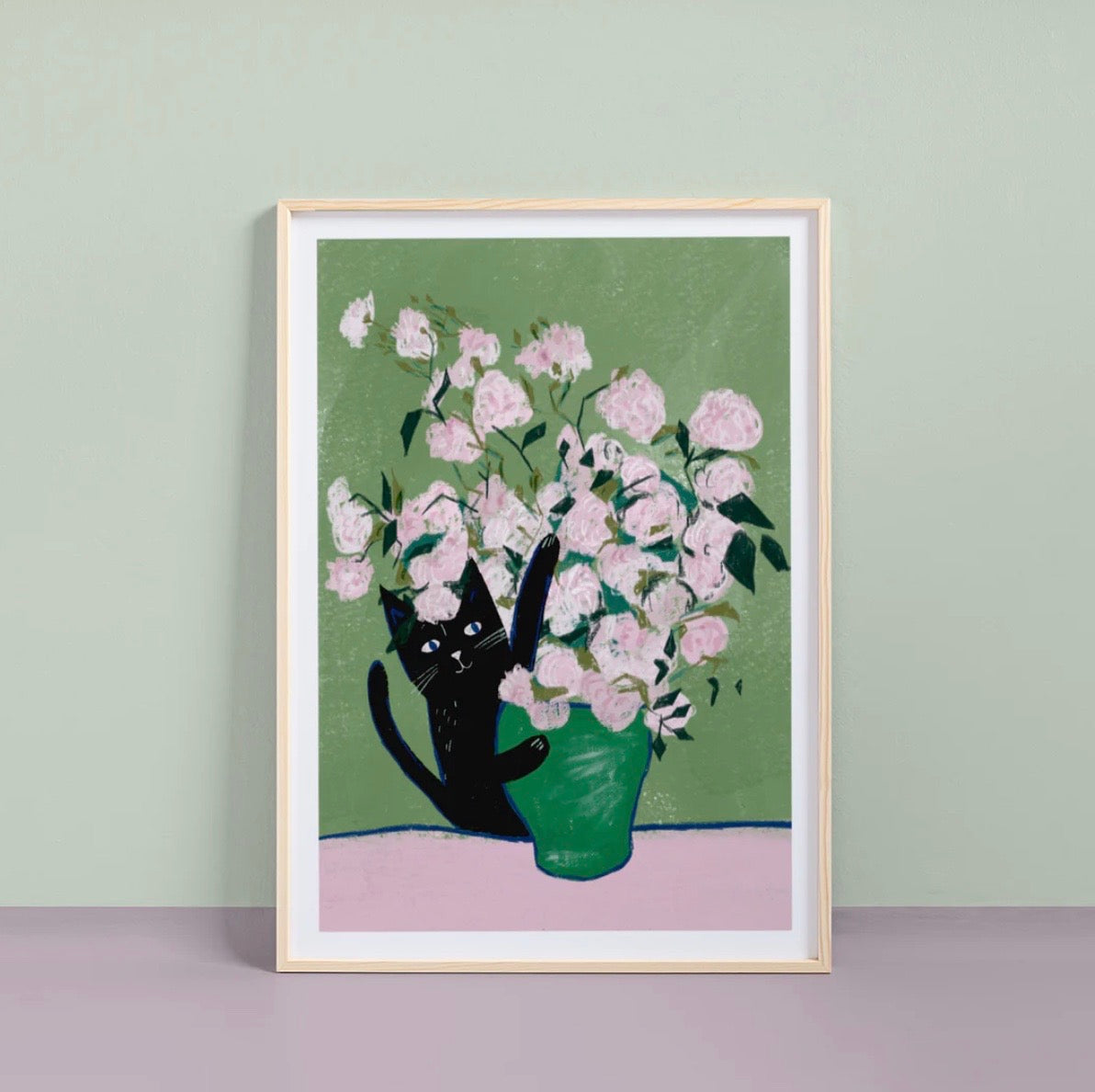 Framed artwork of a black cat with a green vase holding pink flowers on a light green background.