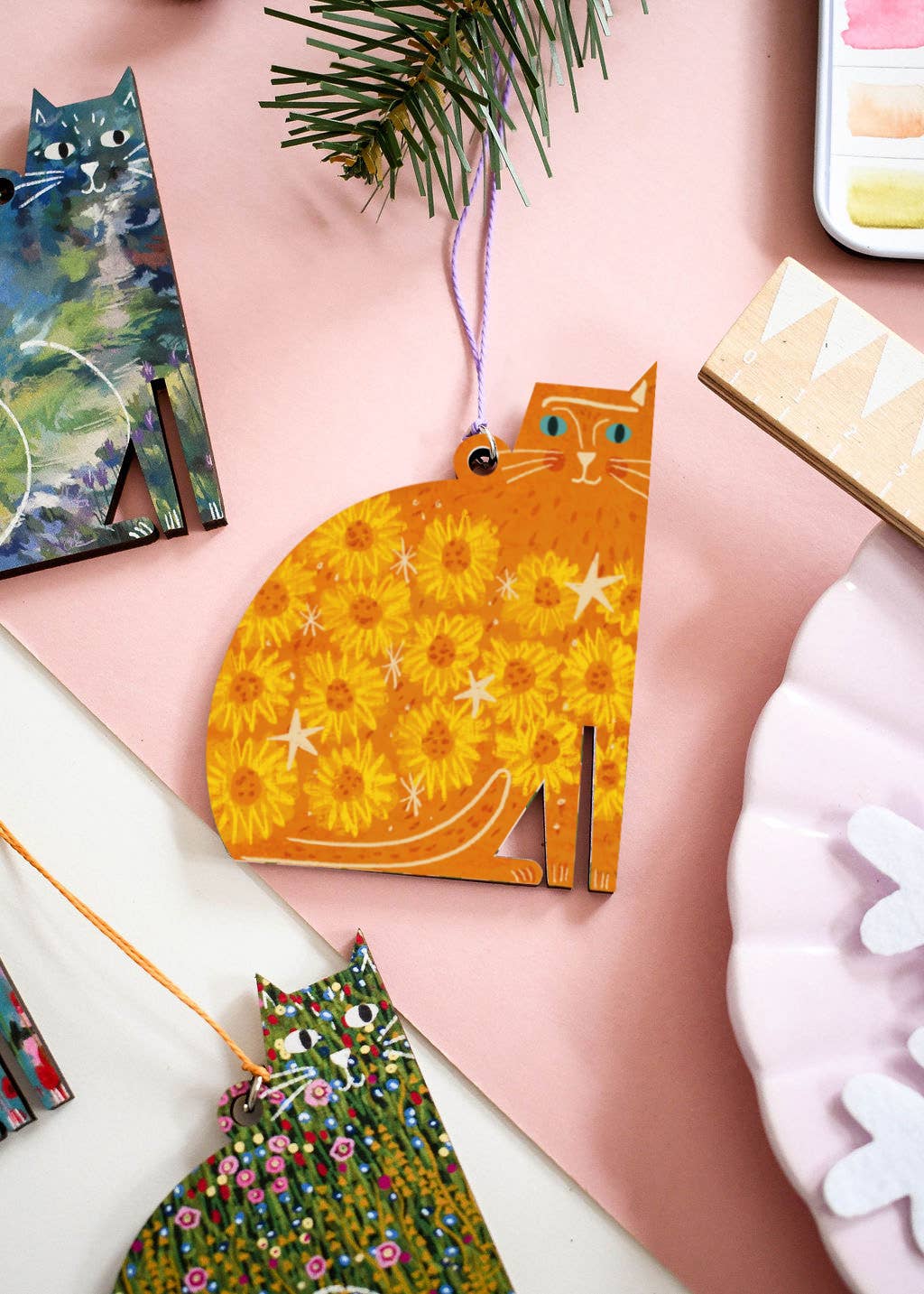 Decorative cat-shaped ornament with floral pattern on a pink surface.