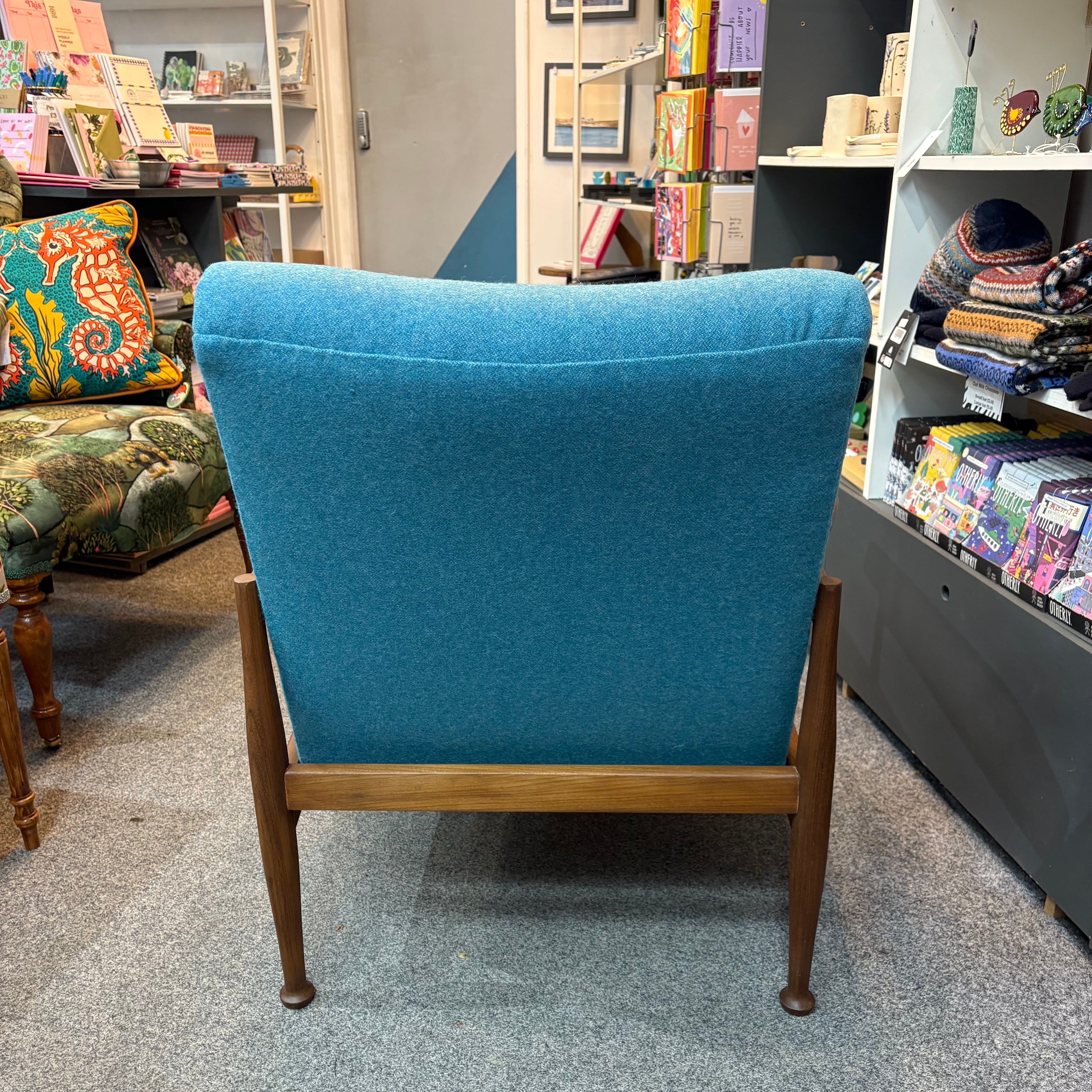 Blue armchair in a store setting with books and other items on shelves.