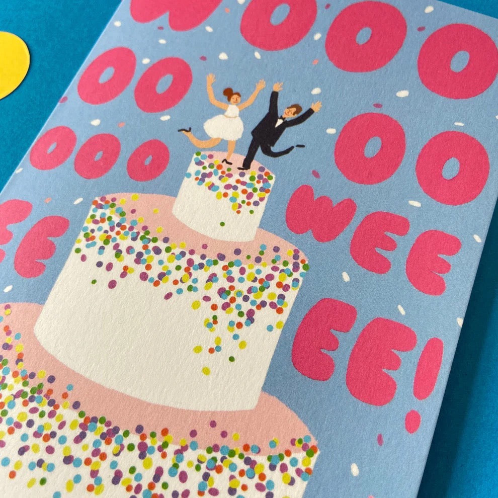Card with a wedding couple on a cake, surrounded by 'OO WEE EE!' text and colourful confetti.