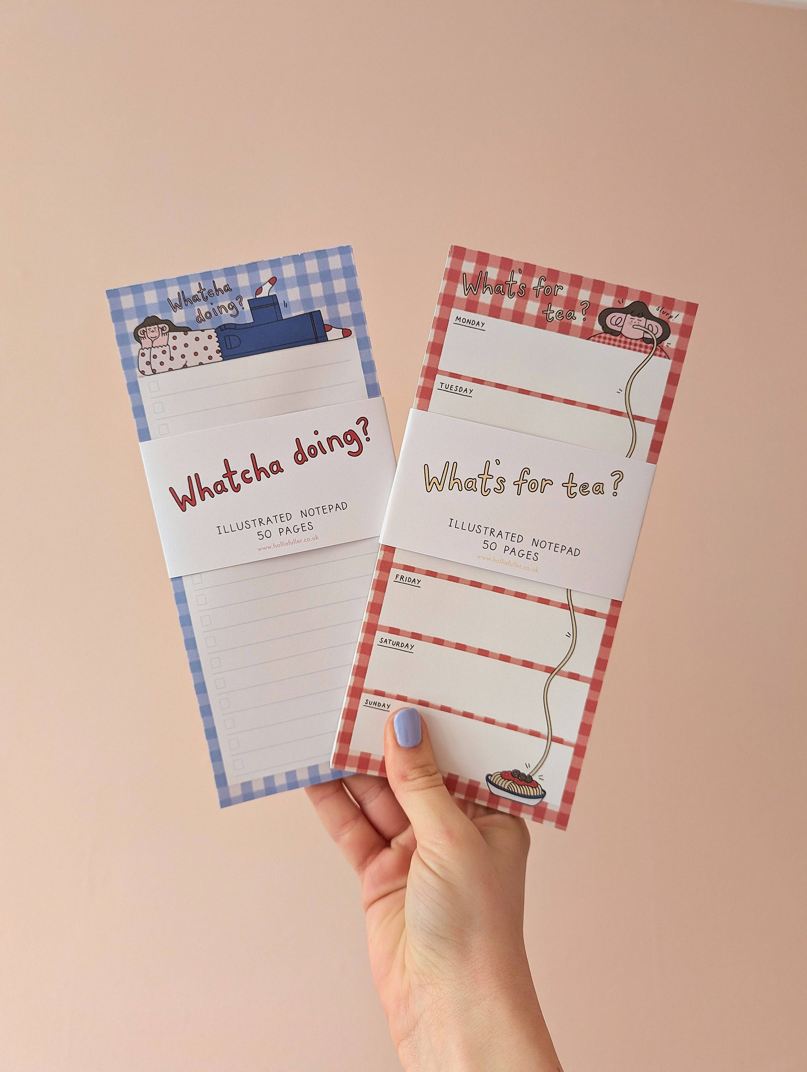 Two illustrated notepads held by a hand against a beige background.