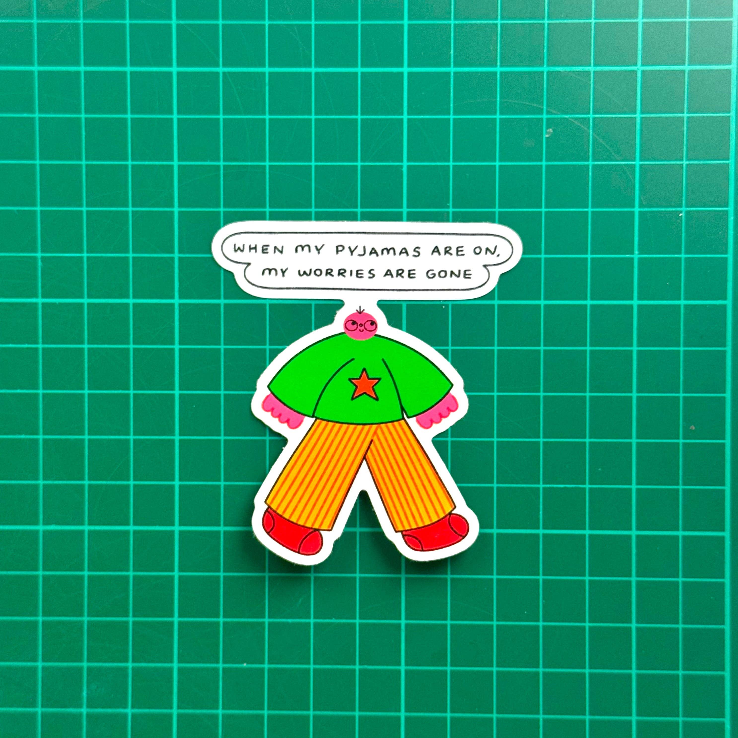 Sticker of a green shirt and orange pants with a speech bubble on a green grid background.