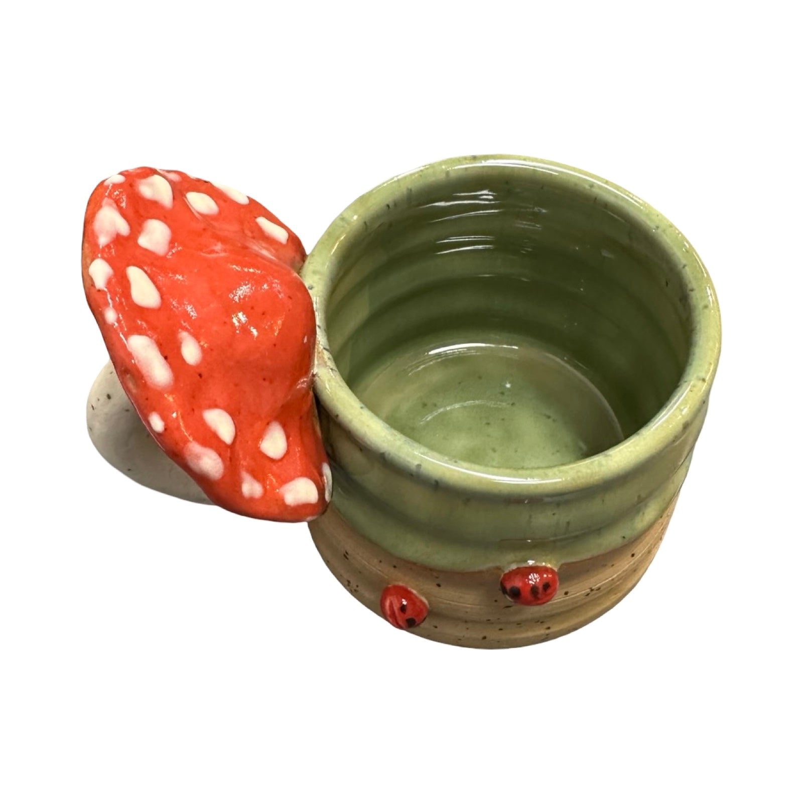Ceramic mug with a red mushroom-shaped handle and ladybirds on a white background.