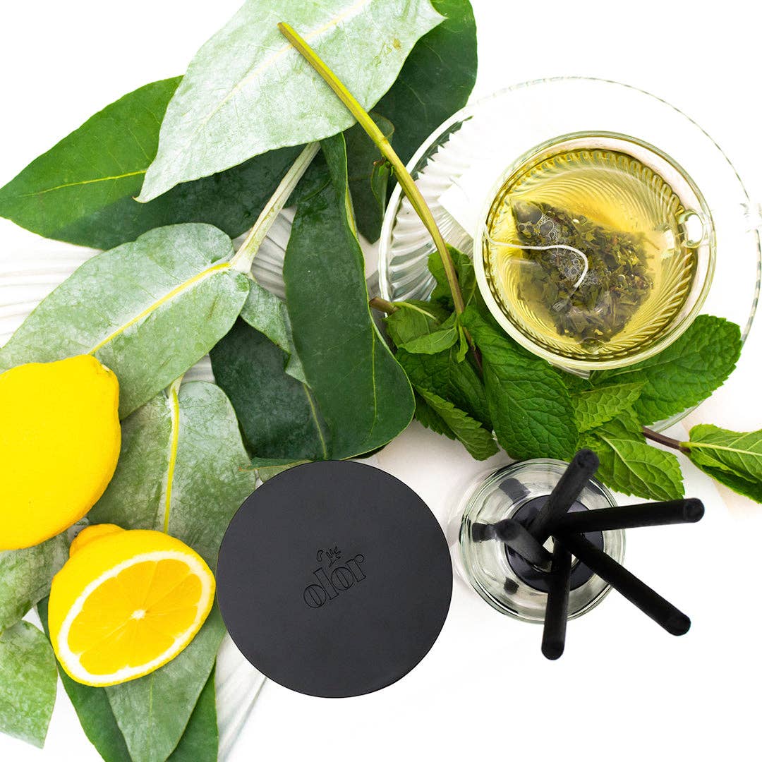 Lemon, mint, leaves and tea next to a reed diffuser.