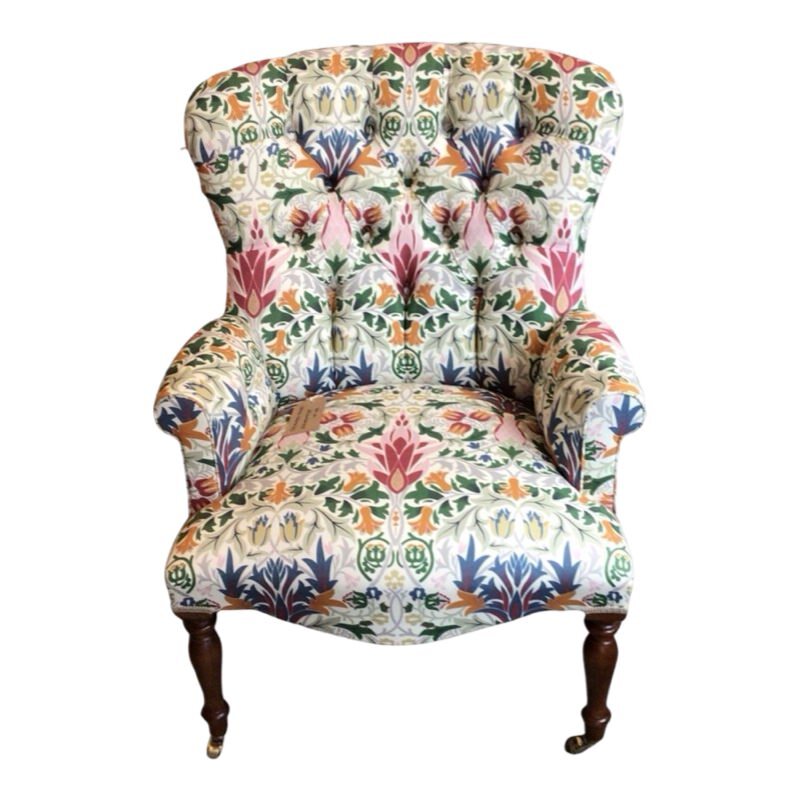 A hand-crafted occasional armchair in cream linen fabric with a multicoloured floral William Morris inspired design, featuring mahogany legs and gold castors.