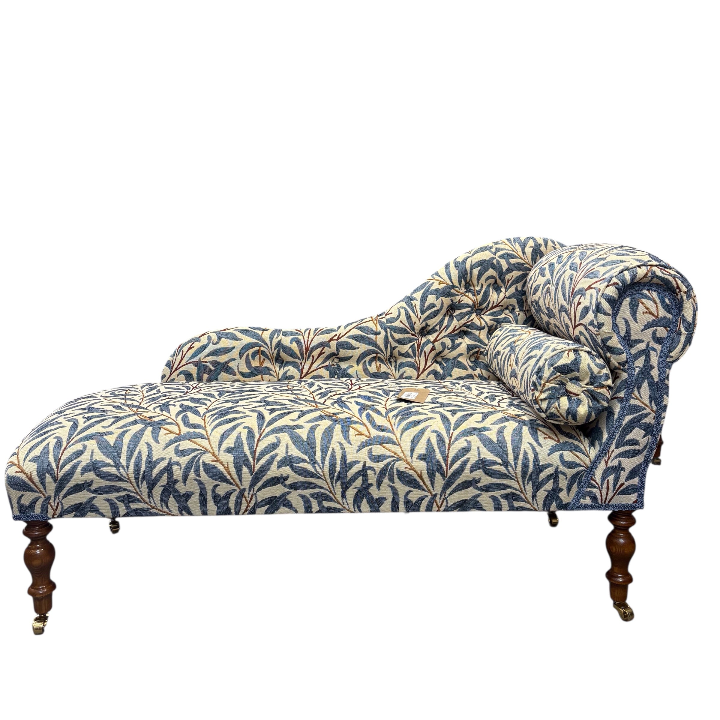 A handcrafted occasional chaise lounge in fabulous&nbsp;woven William Morris It is covered in beautiful William Morris Willow Bough tapestry-style fabric in navy blue and cream. It is finished with navy blue binding and has mahogany-stained wooden legs. The chaise lounge also comes with a removable bolster cushion and brass coloured castors.