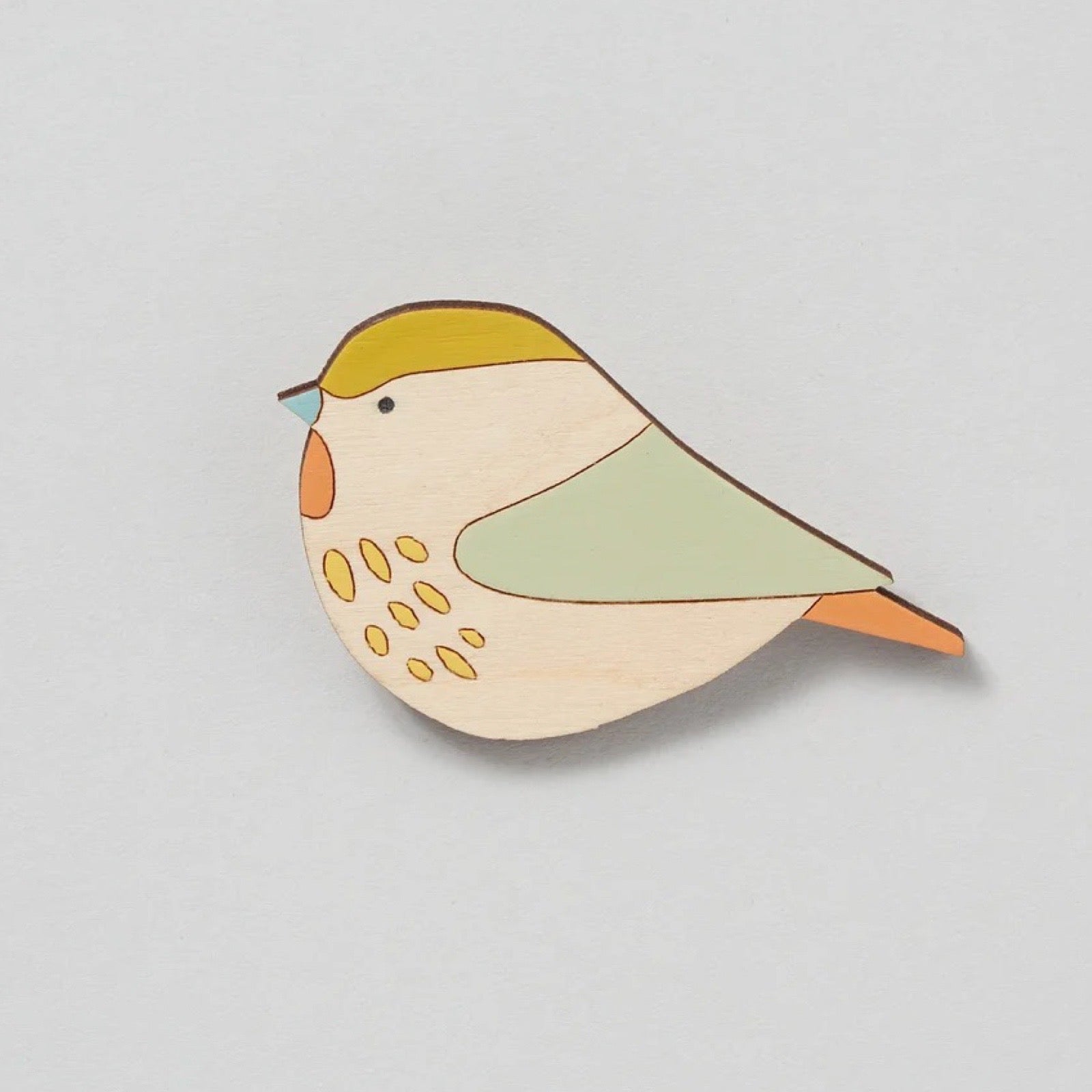 Colourful bird brooch on a light grey background.