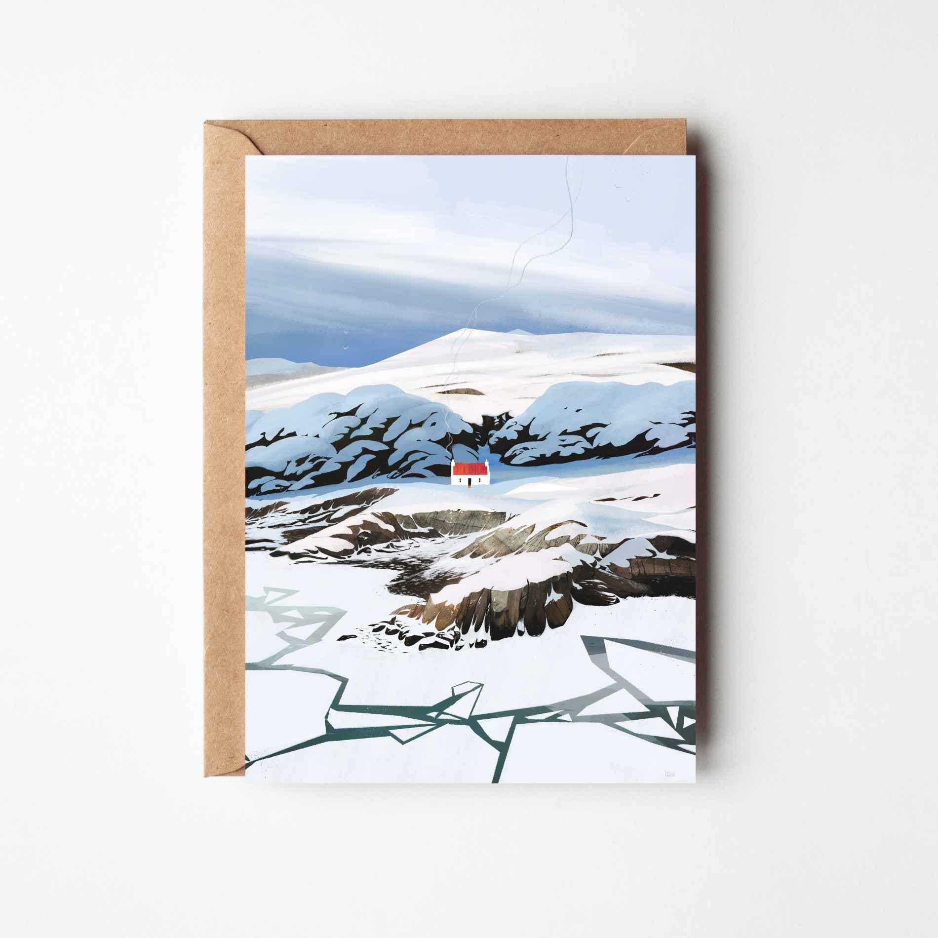 A landscape greeting card featuring a snowy mountain scene with a small red-roofed house, shown with a brown kraft envelope against a light grey background.