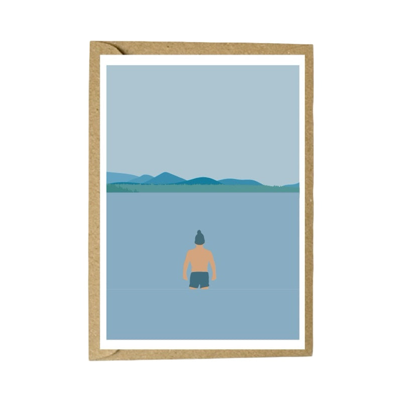 Framed artwork of a person standing by a lake with mountains in the background.
