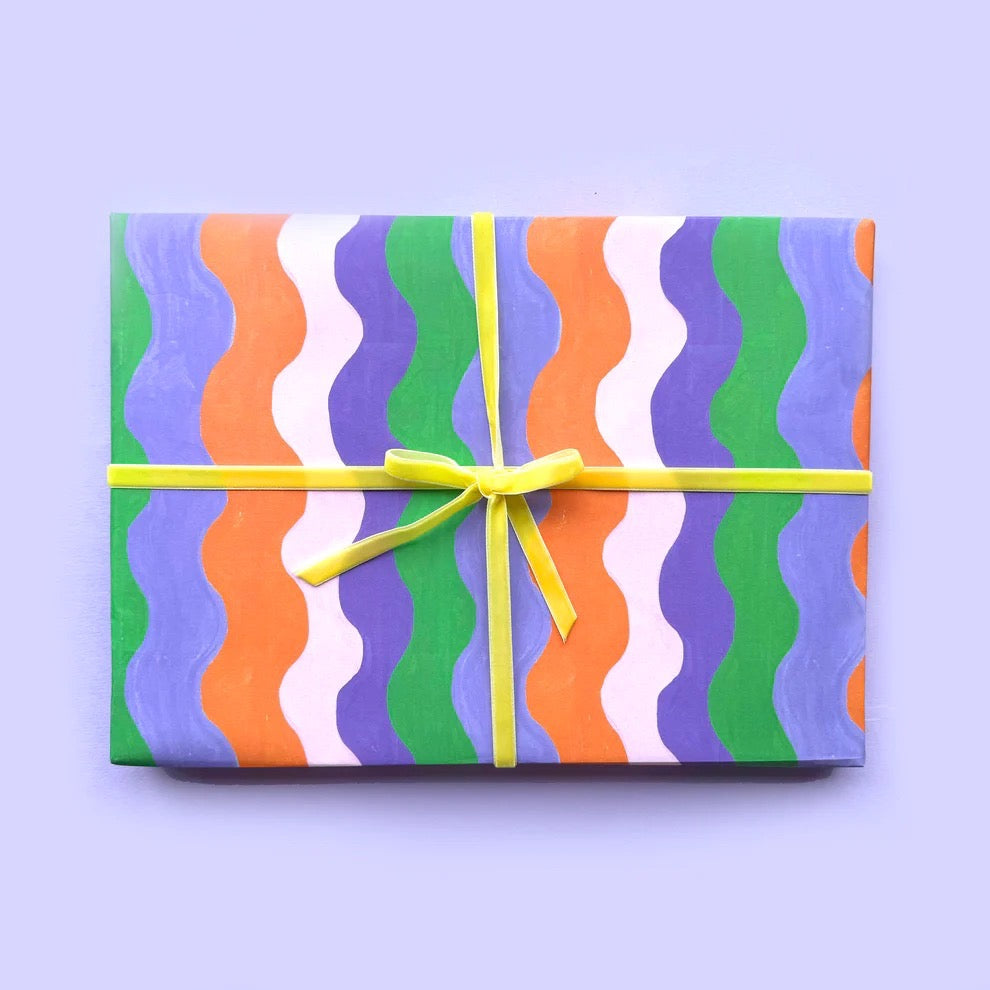 Gift box with colourful wavy pattern and yellow ribbon on a light purple background.